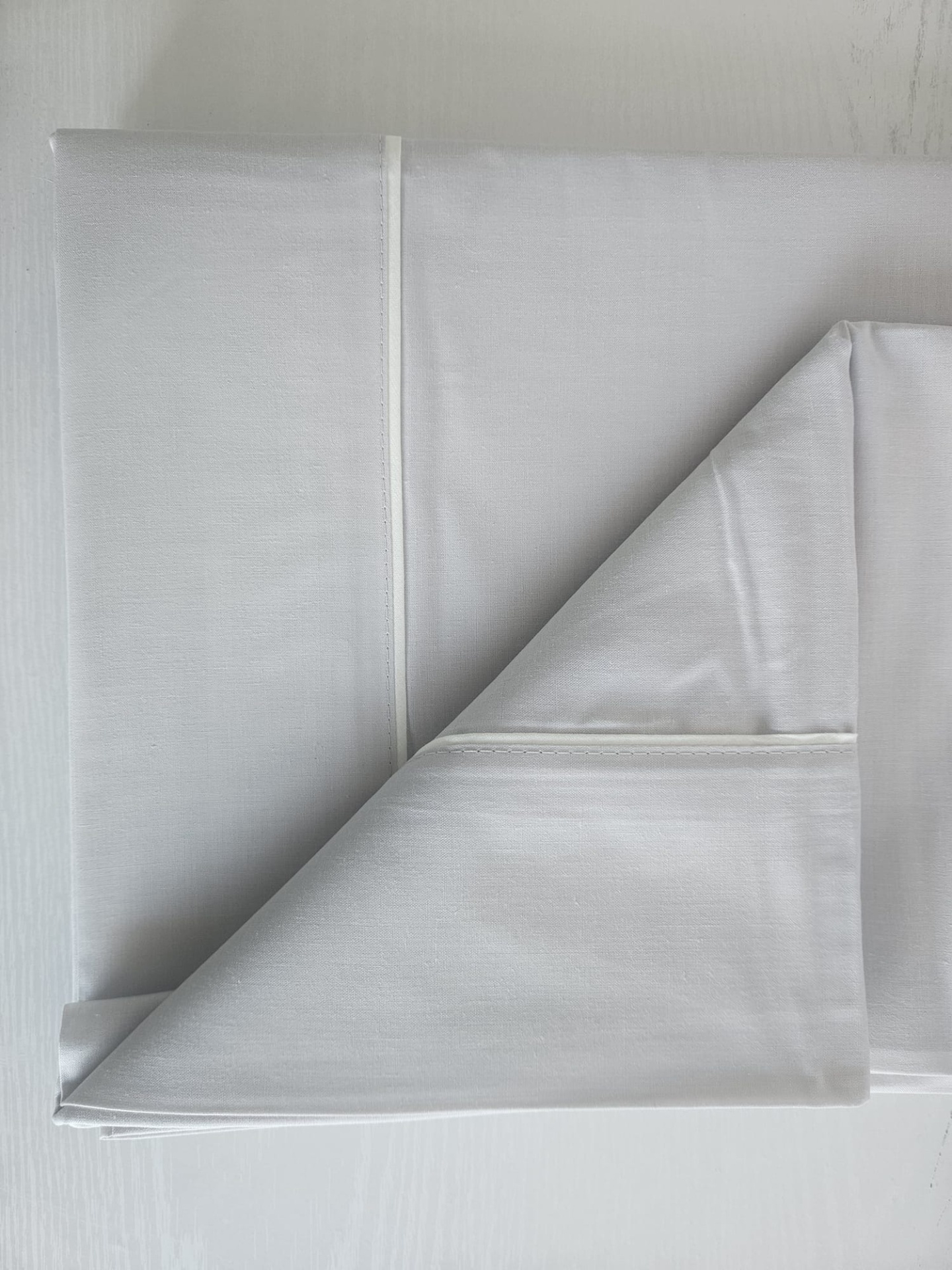 Guardanapo ou pano de tecido branco com costuras e detalhes em linha branca.