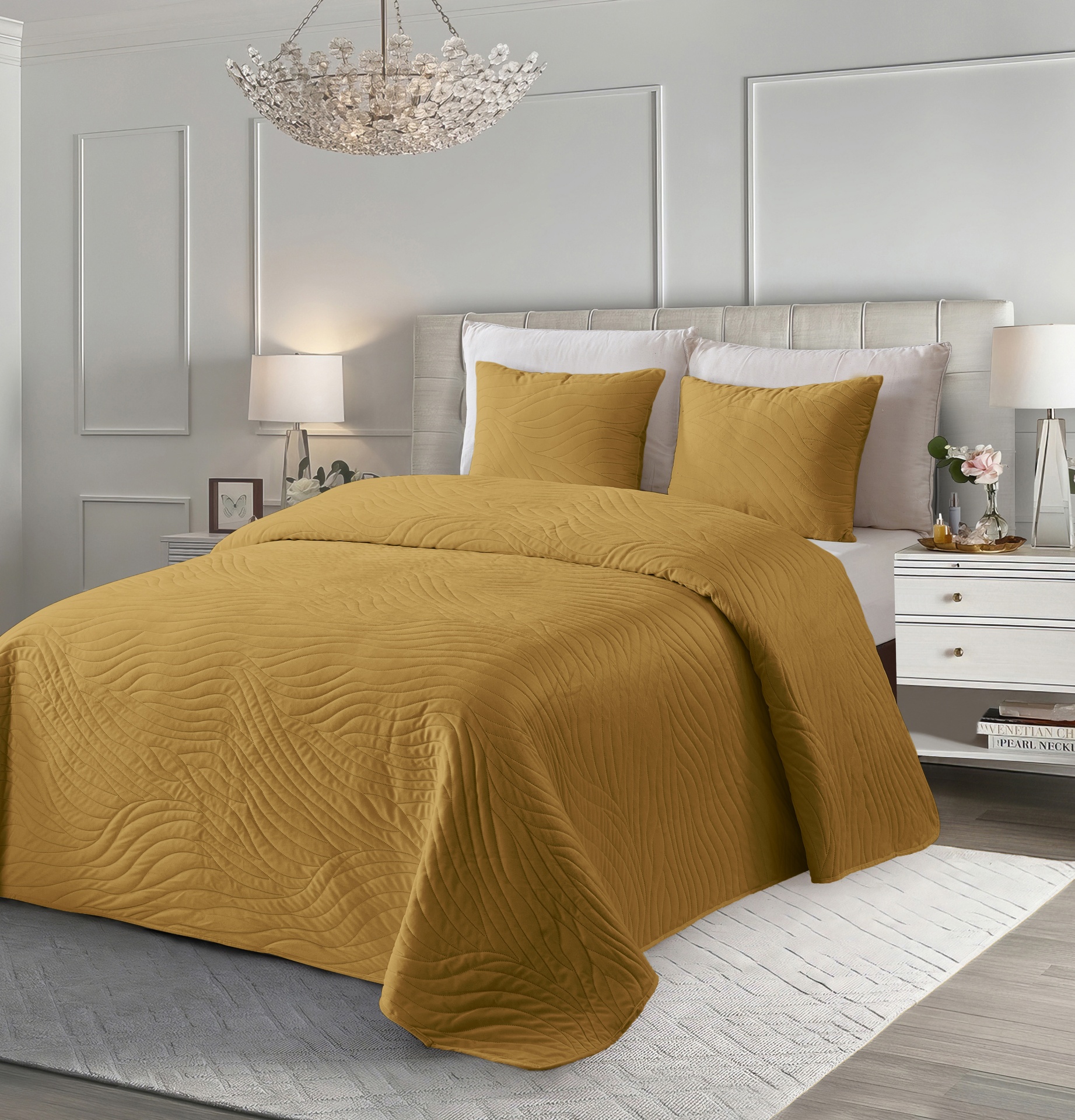 Cama com colcha e almofadas mostarda com padrão ondulado em quarto decorado com mobília branca e iluminação suave