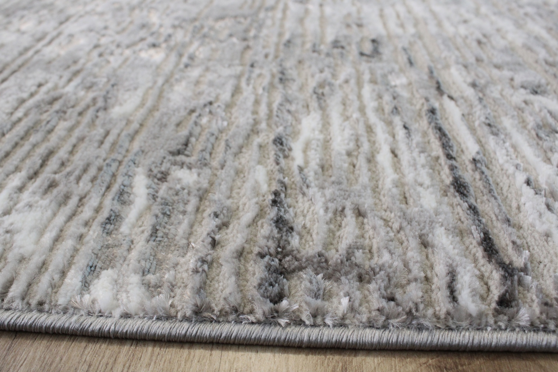 Tapete decorativo cinza, bege e branco com padrão abstracto e textura felpuda