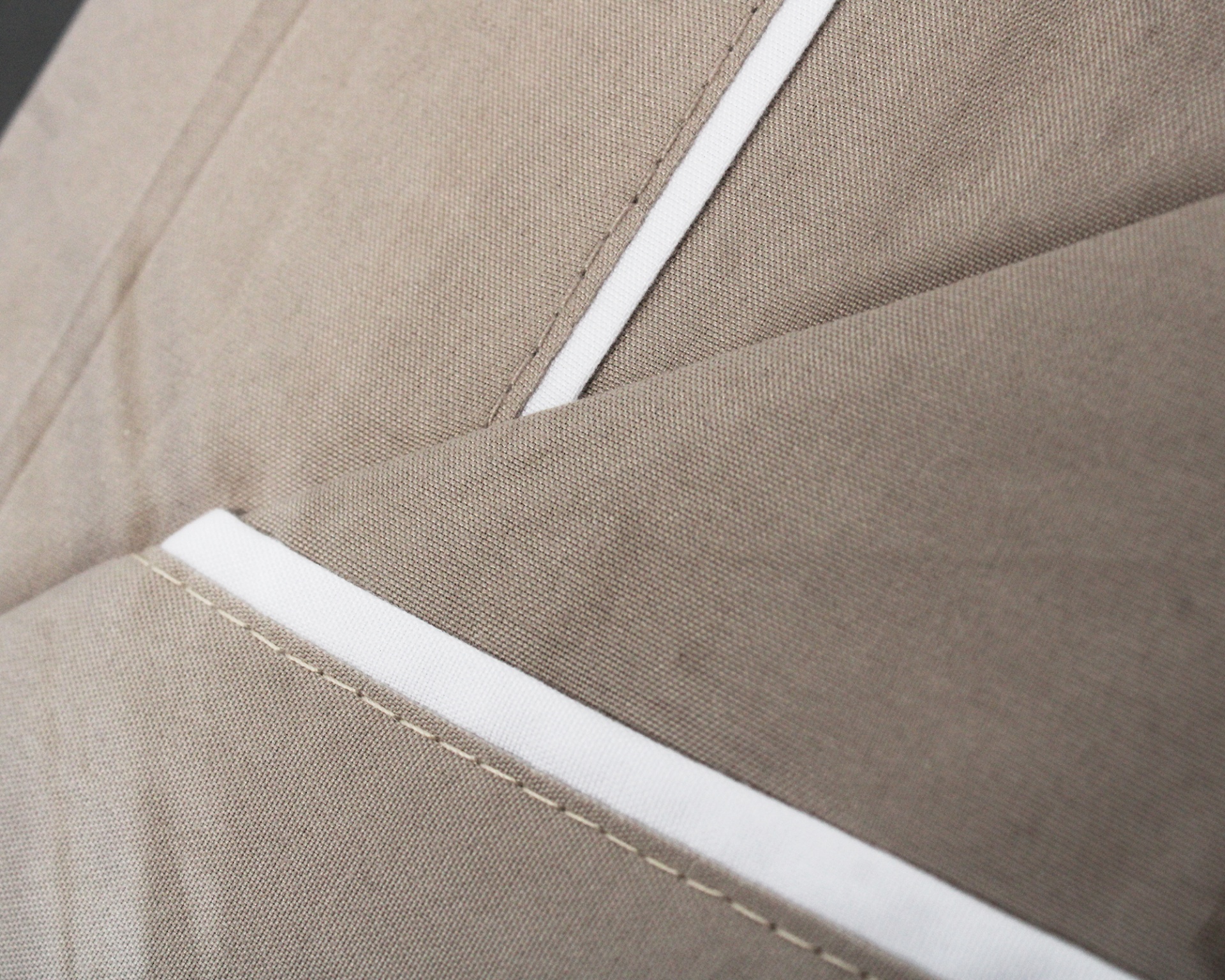 Tecido cinzento-bege com costuras brancas em close-up