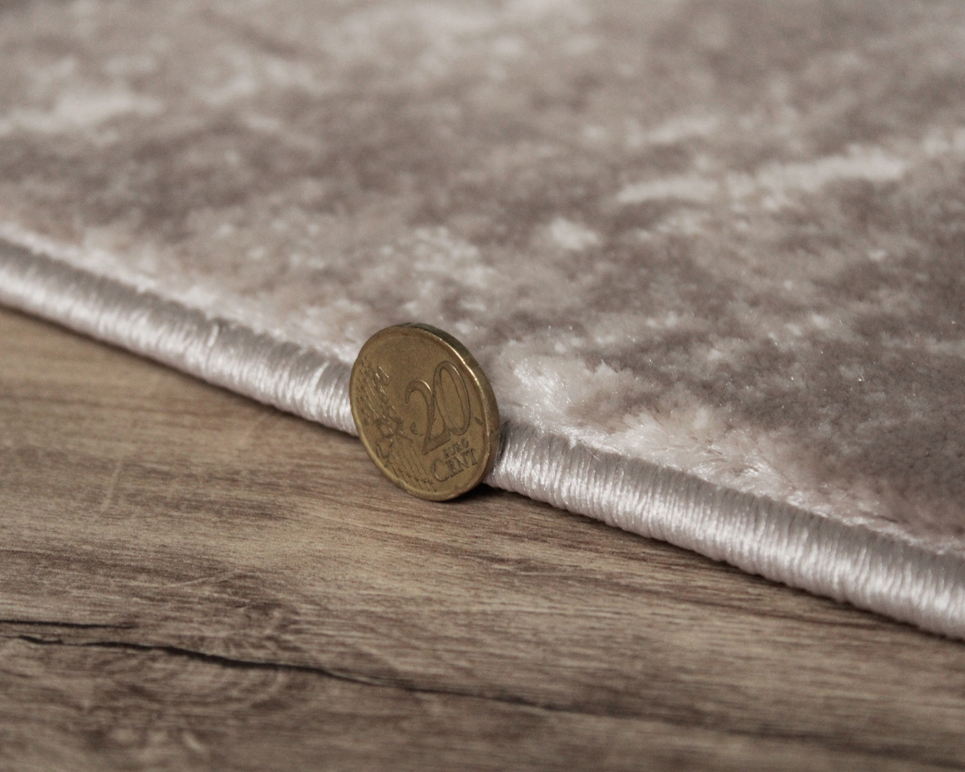 Tapete cinzento macio com moeda de 20 cêntimos perto da borda