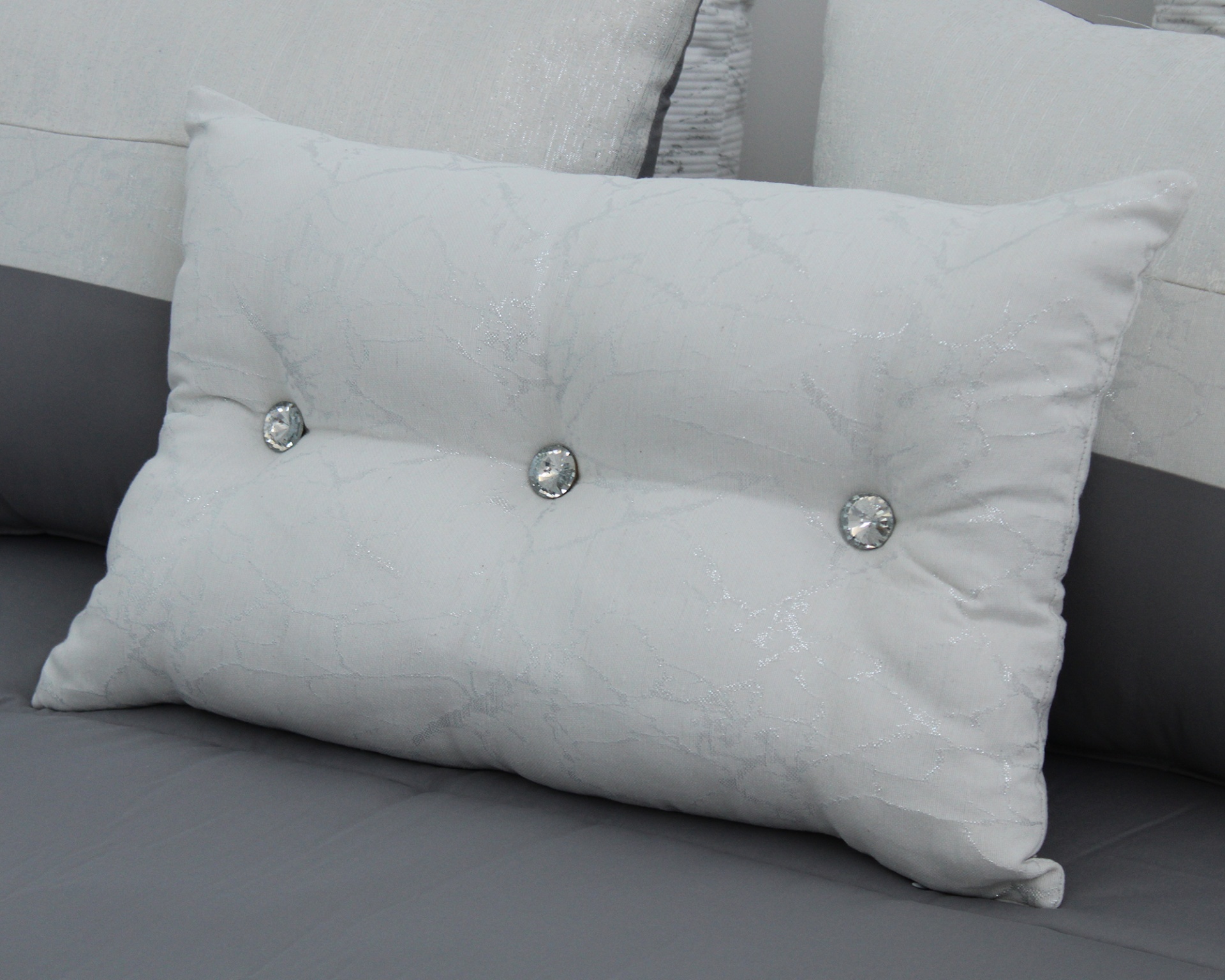 Almofada branca decorativa com botões sobre sofá cinza
