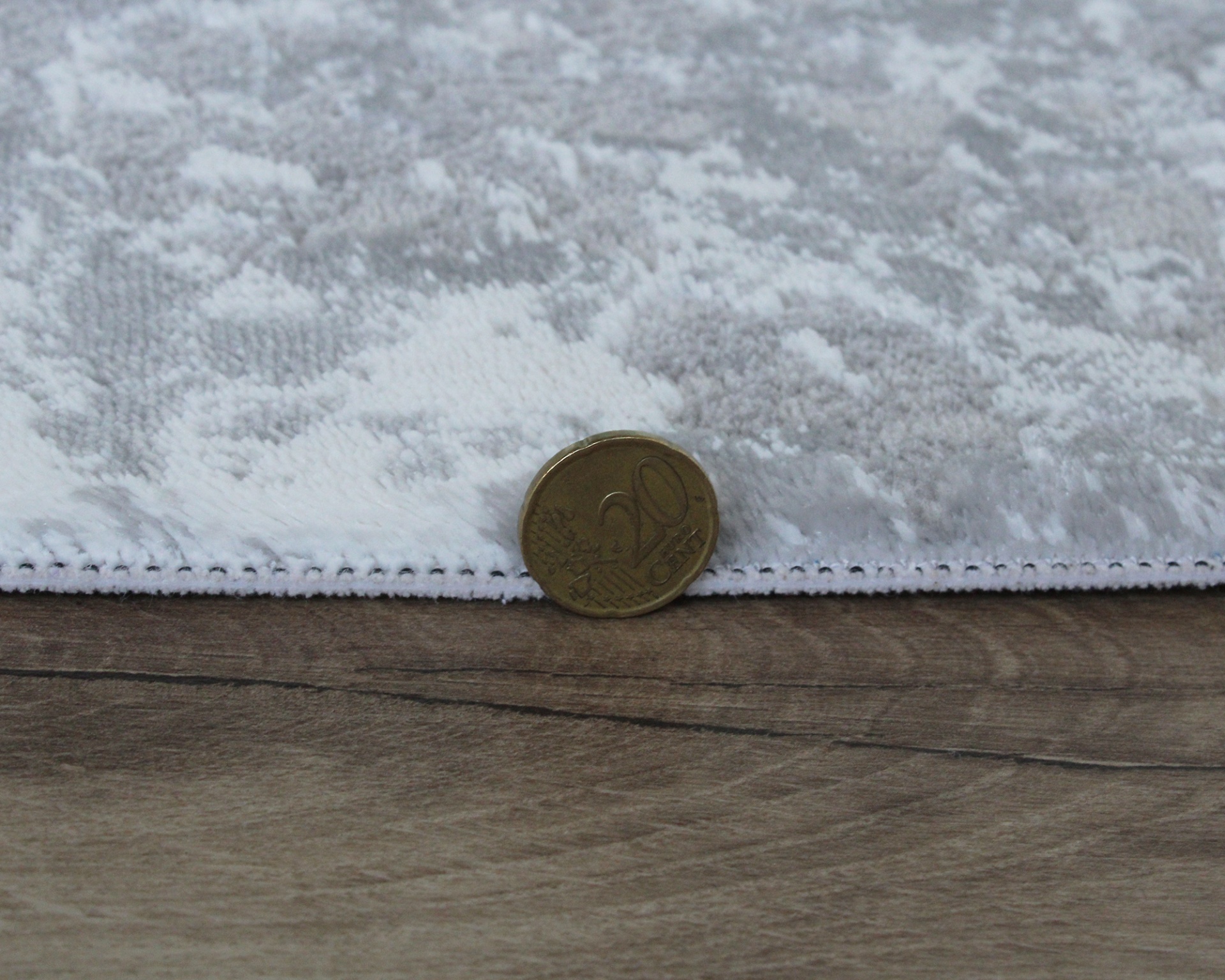 tecido branco e cinzento com padrão floral em relevo e moeda de 20 centavos