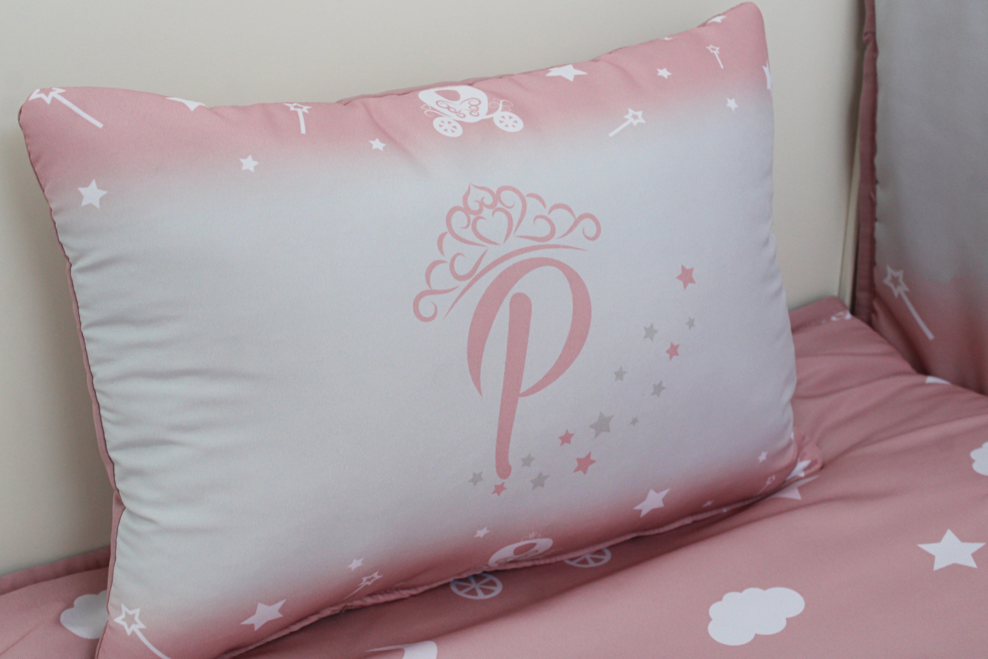 Almofada retangular com padrão rosa e branco, letra P com coroa