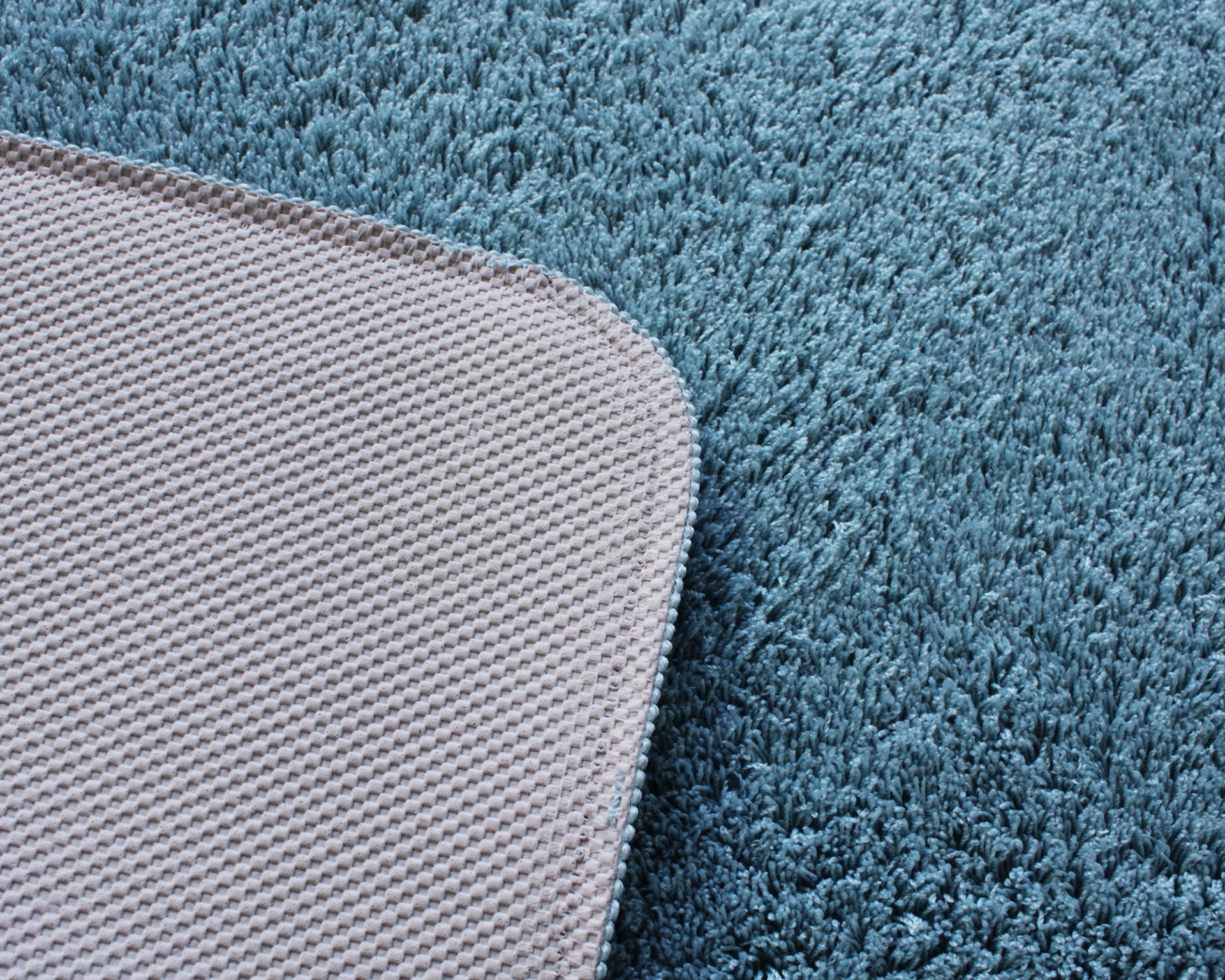 Tapete azul macio com base cinza anti-derrapante em close-up