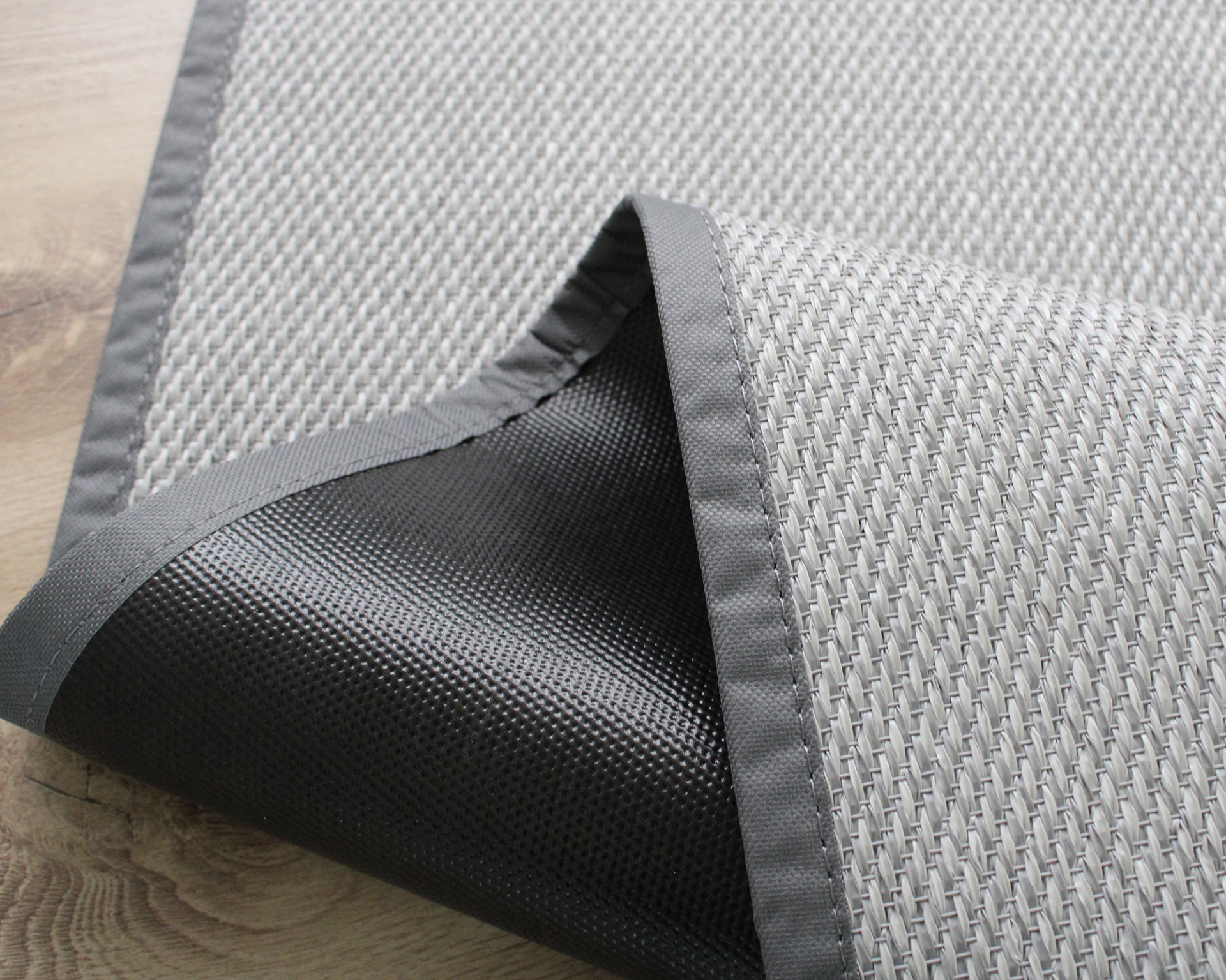 Tapete cinzento com parte inferior antiderrapante num chão de madeira