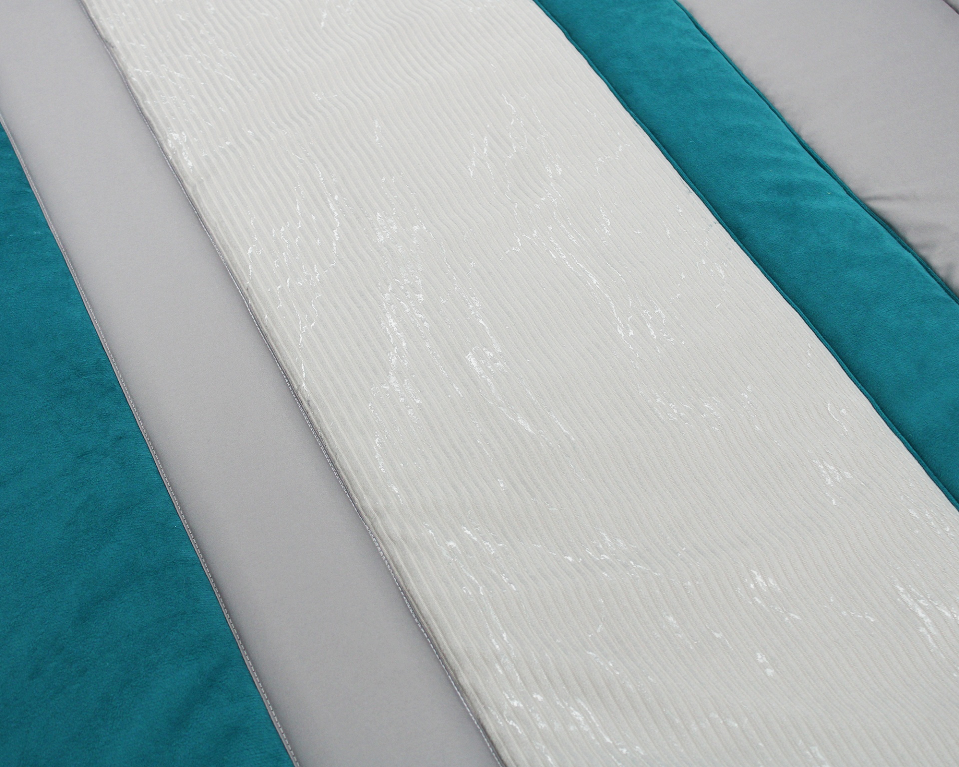 Colchão branco texturizado sobre base azul e superfície cinza