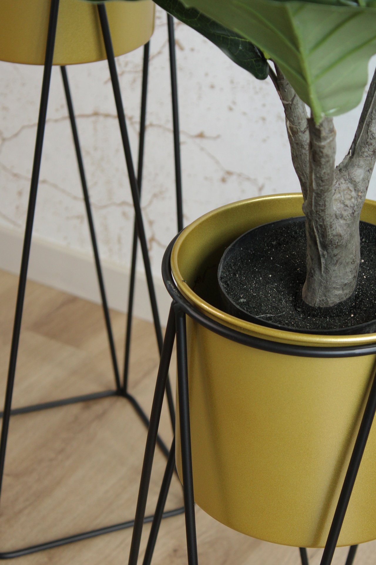 Suportes de plantas em metal com vasos dourados e plantas verdes