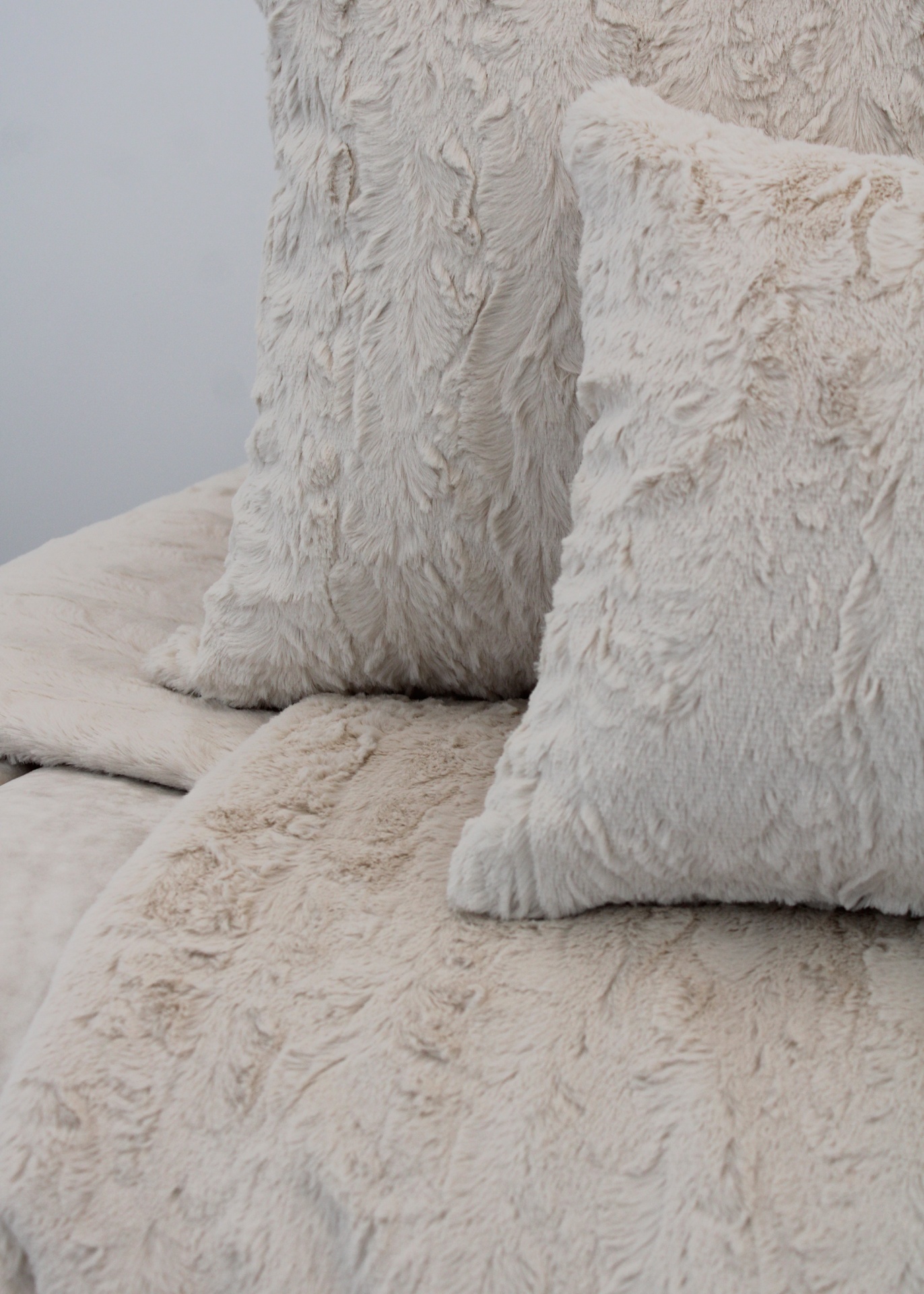 Almofadas creme macias em tecido felpudo sobre sofá revestido semelhante