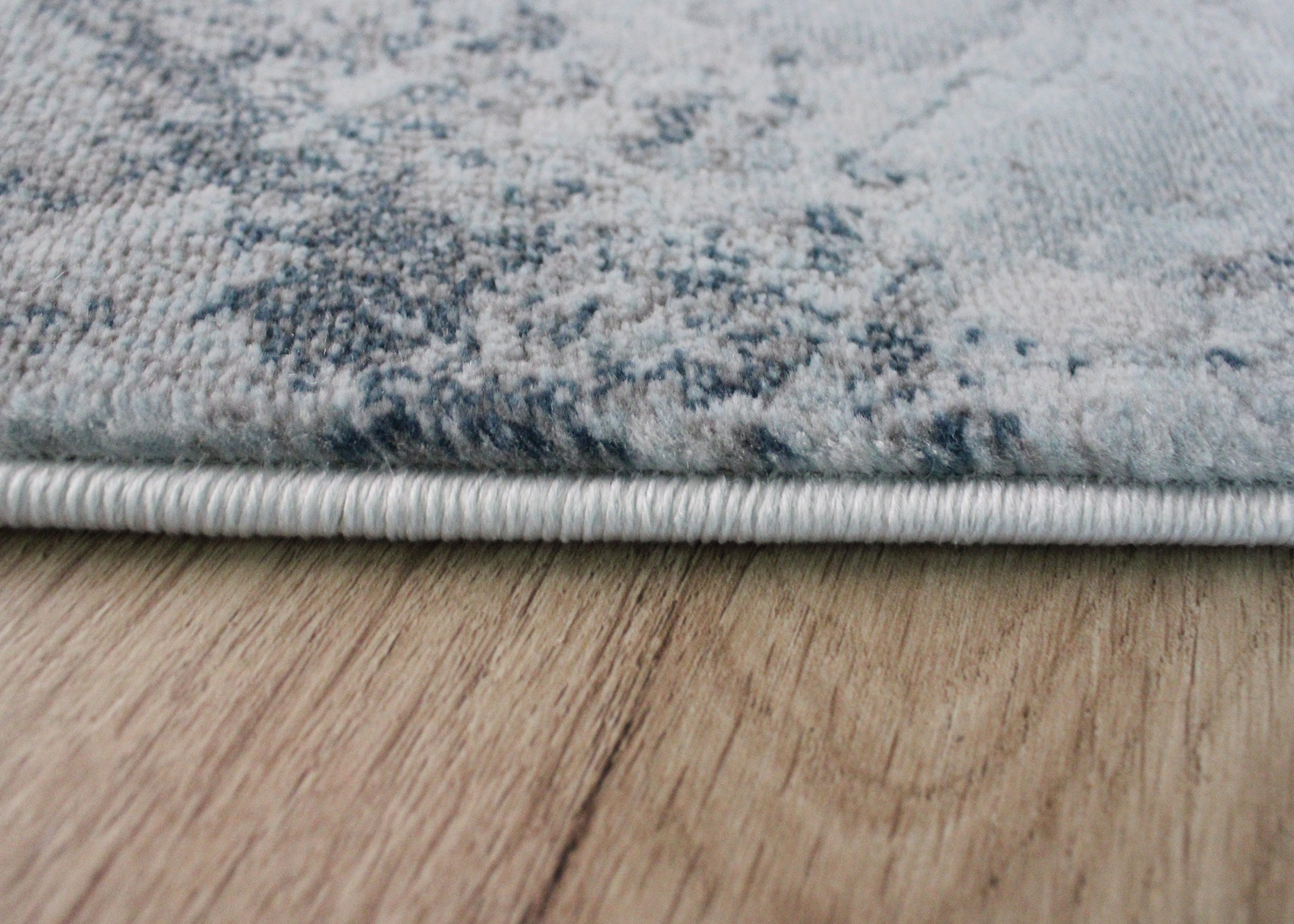 Tapete azul claro com padrão abstrato sobre chão de madeira clara