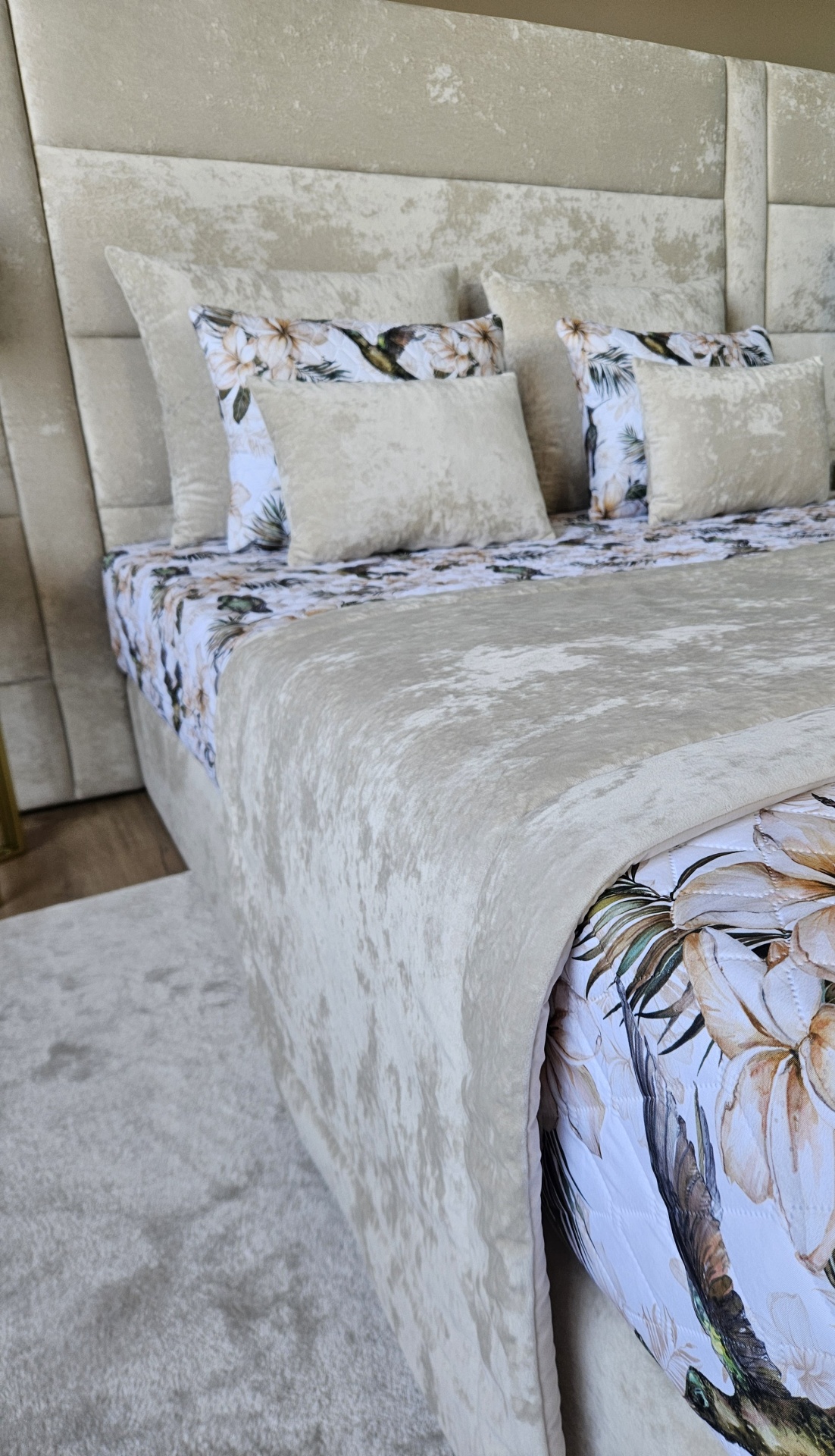 Cama com cabeceira e roupa de cama bege aveludada e floral