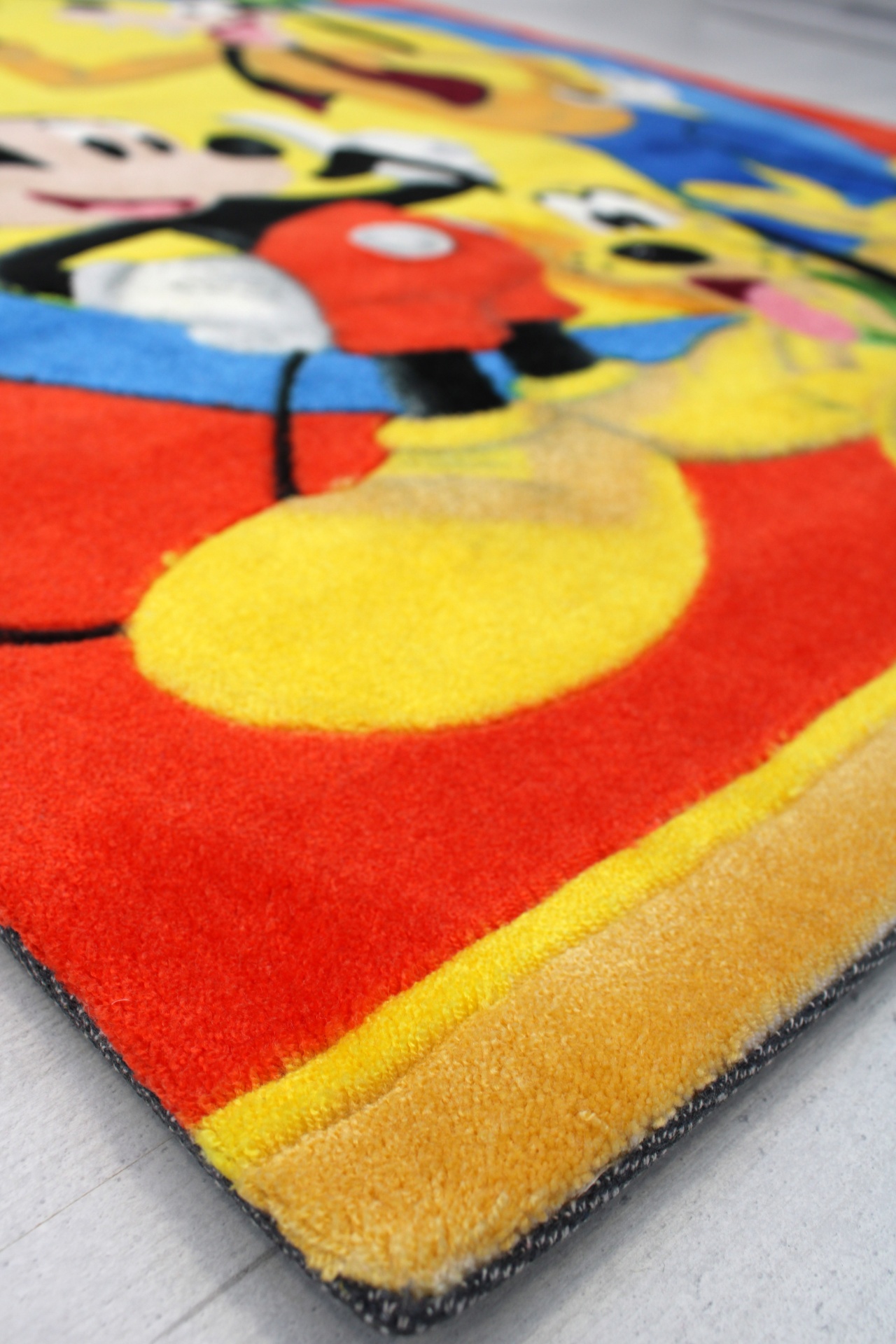 Tapete felpudo colorido com personagens da Disney sobre chão claro