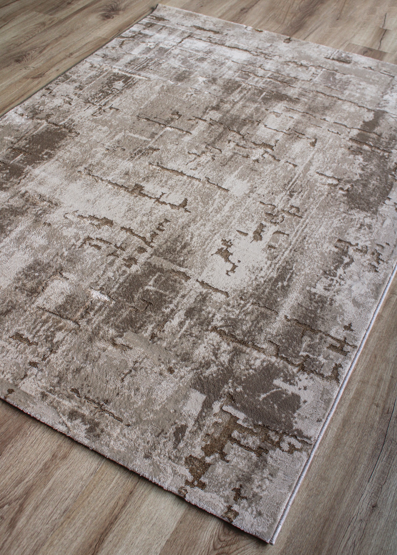 Tapete abstrato em tons de bege, castanho e cinzento sobre chão de madeira
