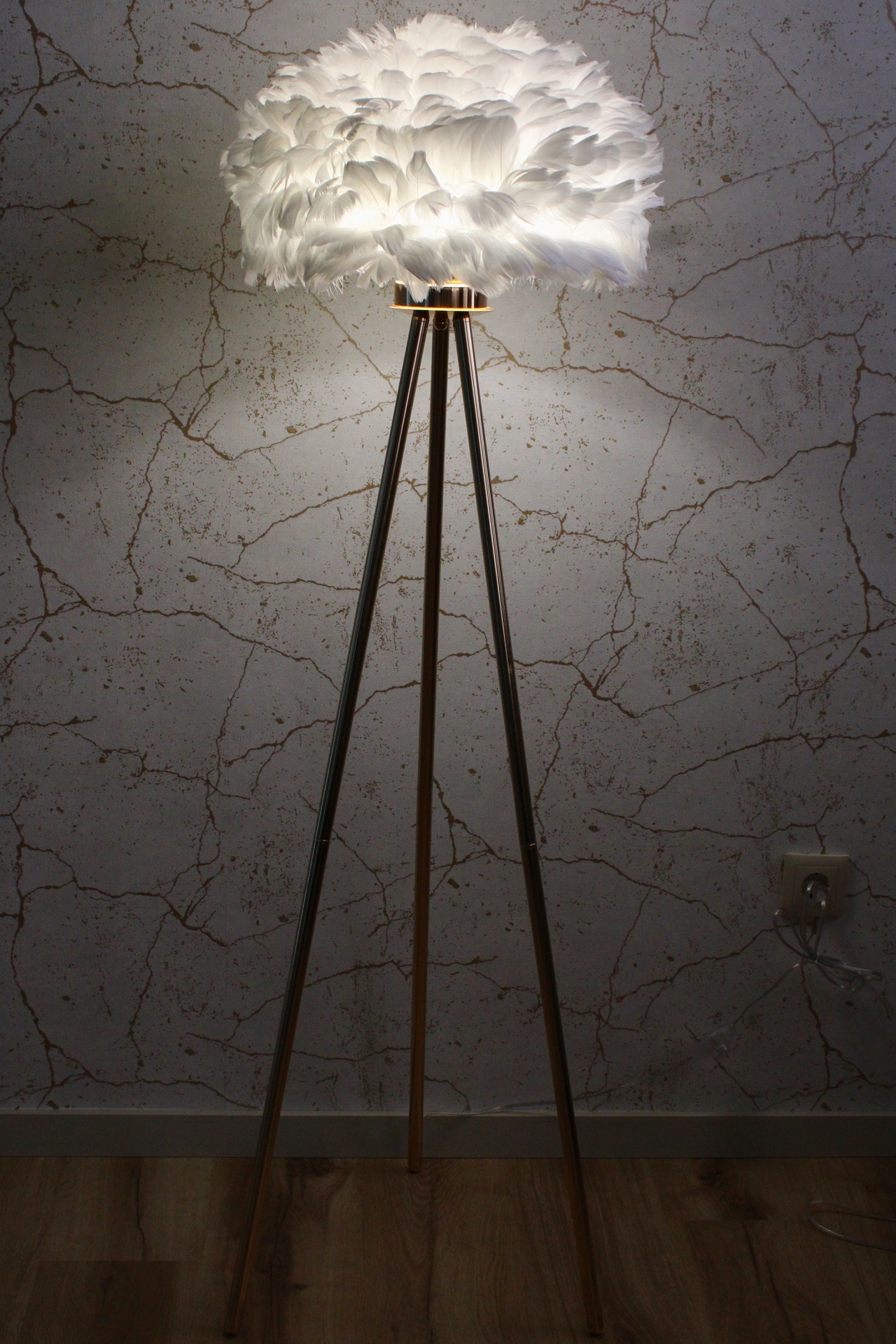 Candeeiro de pé com base tripé de madeira e cúpula de penas brancas iluminado