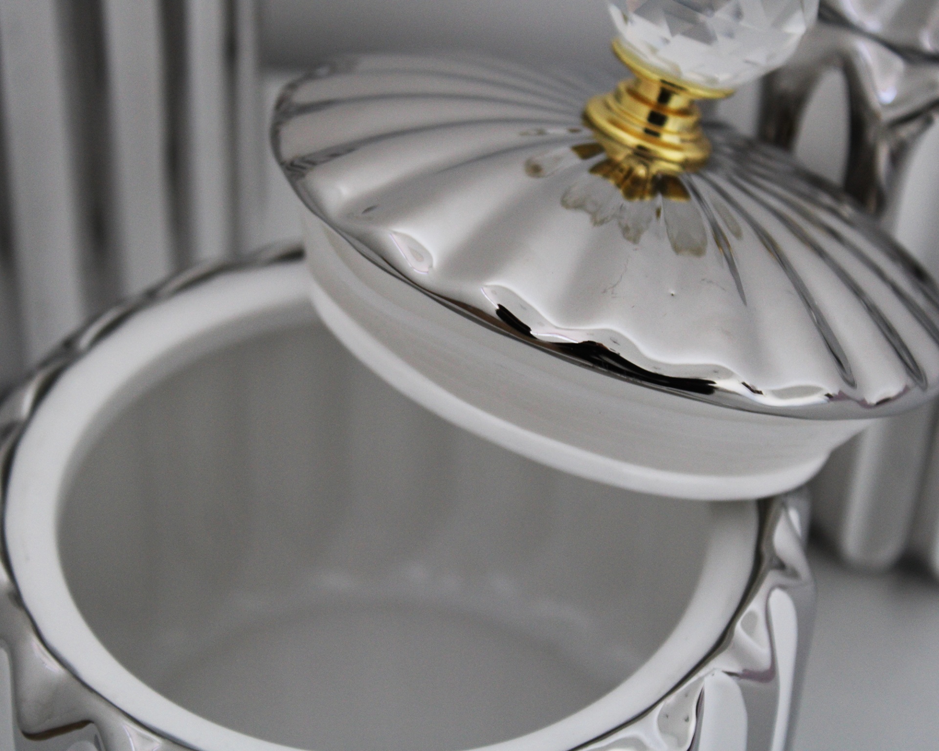 Pote de porcelana branca com tampa metálica prateada e punho em vidro