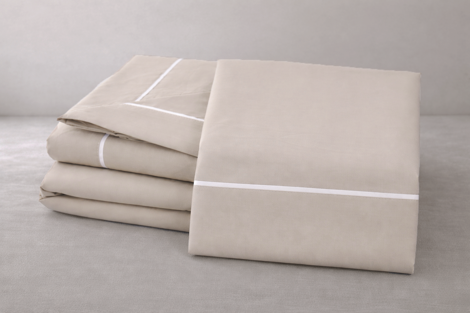 Jogo de cama bege com linhas brancas sobre superfície cinza