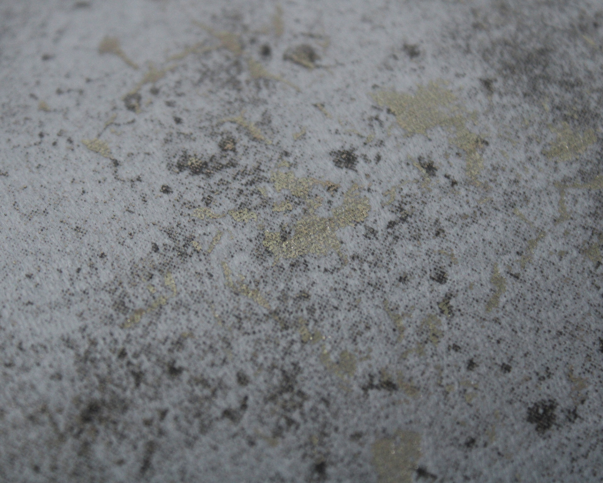 Superfície cinza texturizada com manchas pretas e douradas