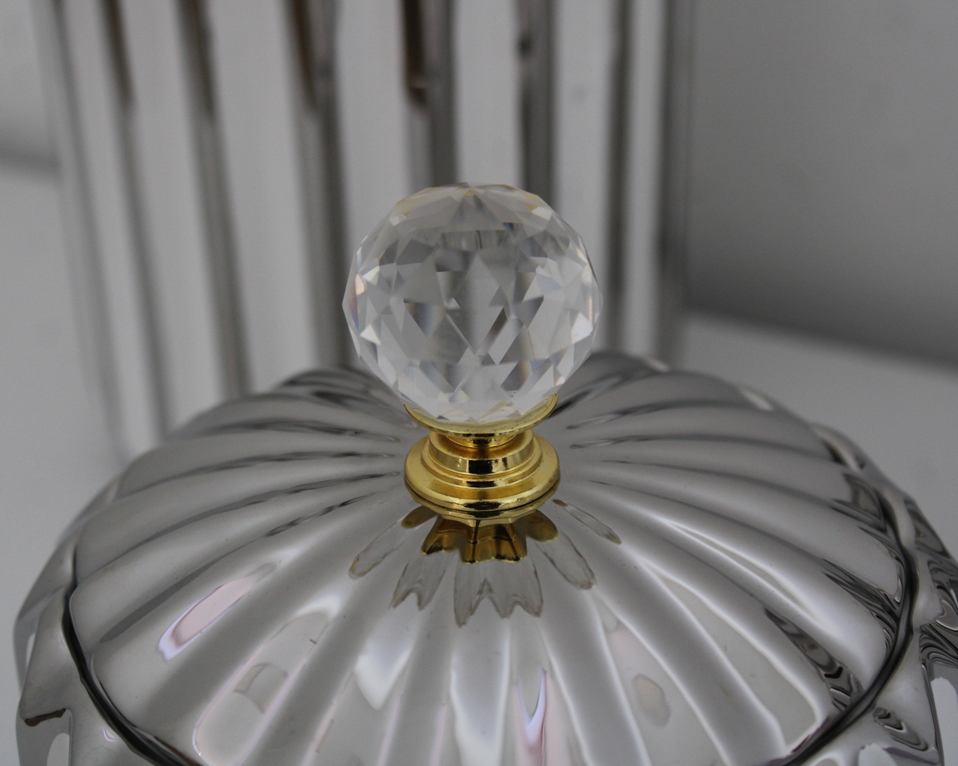 Tampa prateada com puxador facetado transparente e base dourada