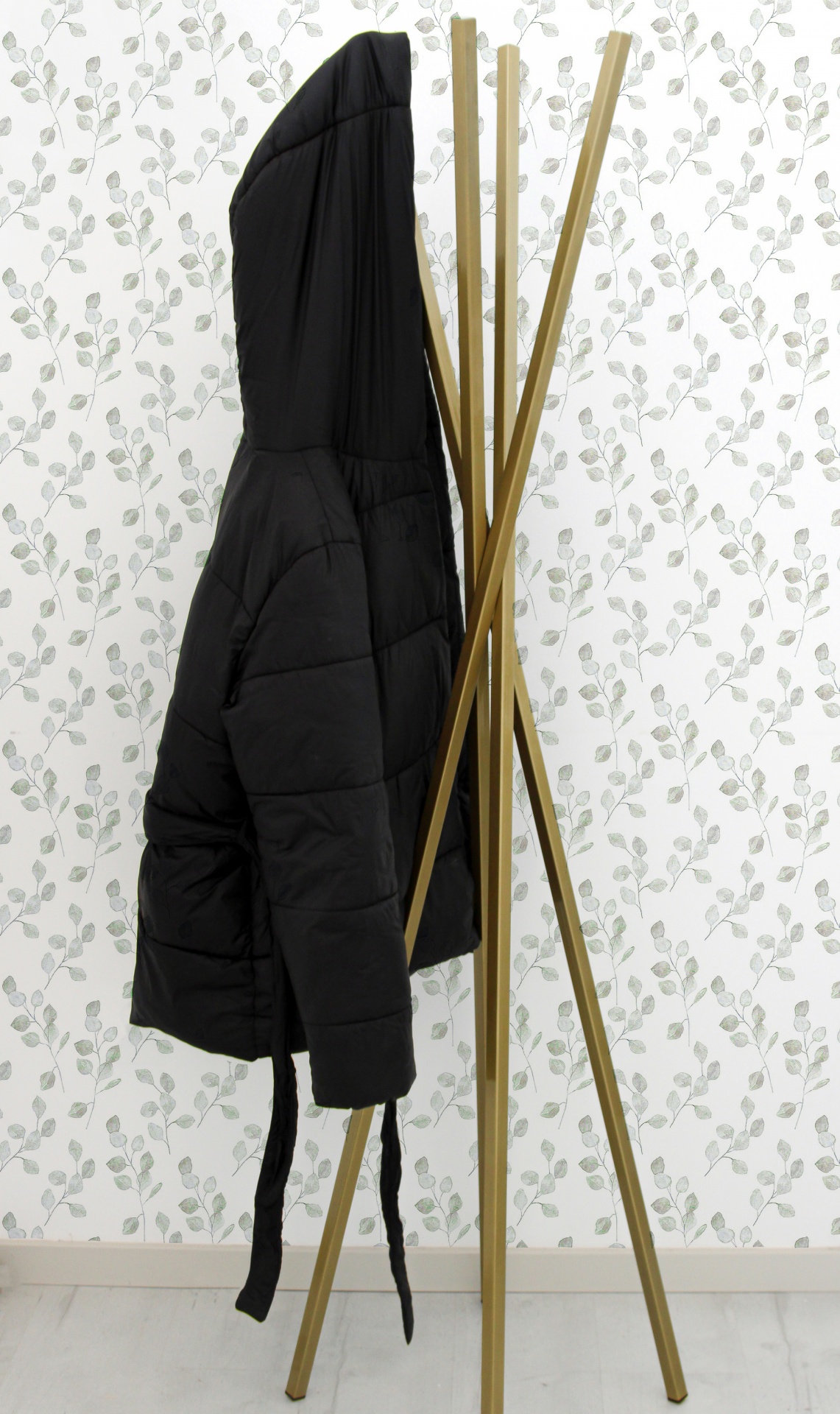 Casaco preto acolchoado pendurado em cabide de madeira dourado