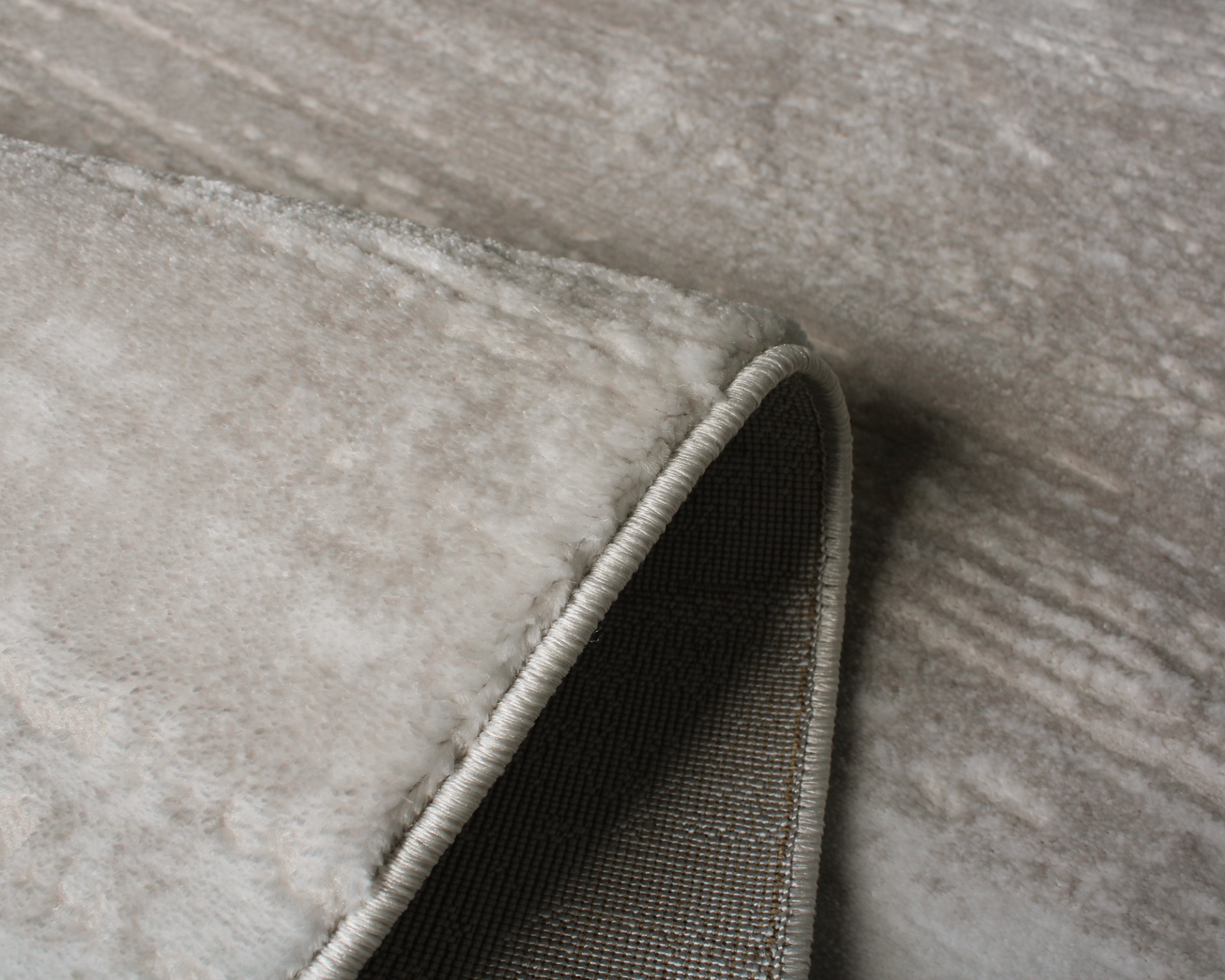 Tapete bege com textura aveludada e bordas costuradas