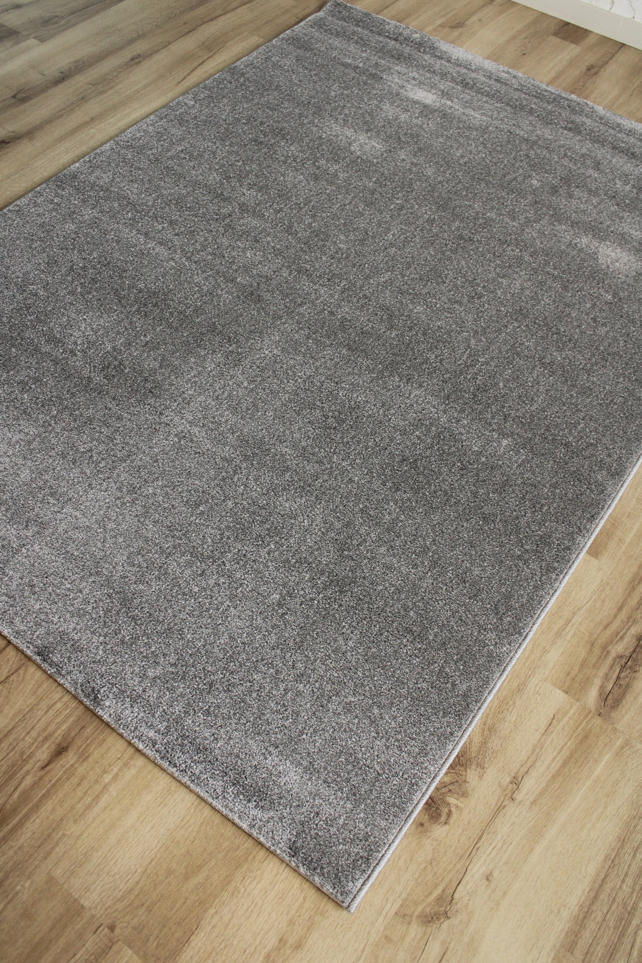 Tapete cinza de pelo curto sobre chão de madeira clara