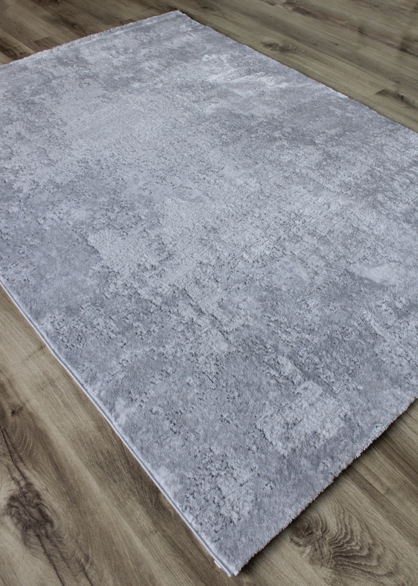 Tapete cinza texturizado sobre chão de madeira clara