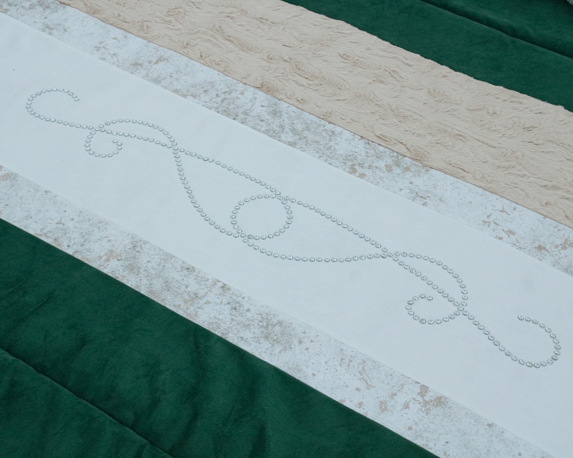 Tecido decorativo verde, bege e branco com padrão ornamental feito de pedrinhas