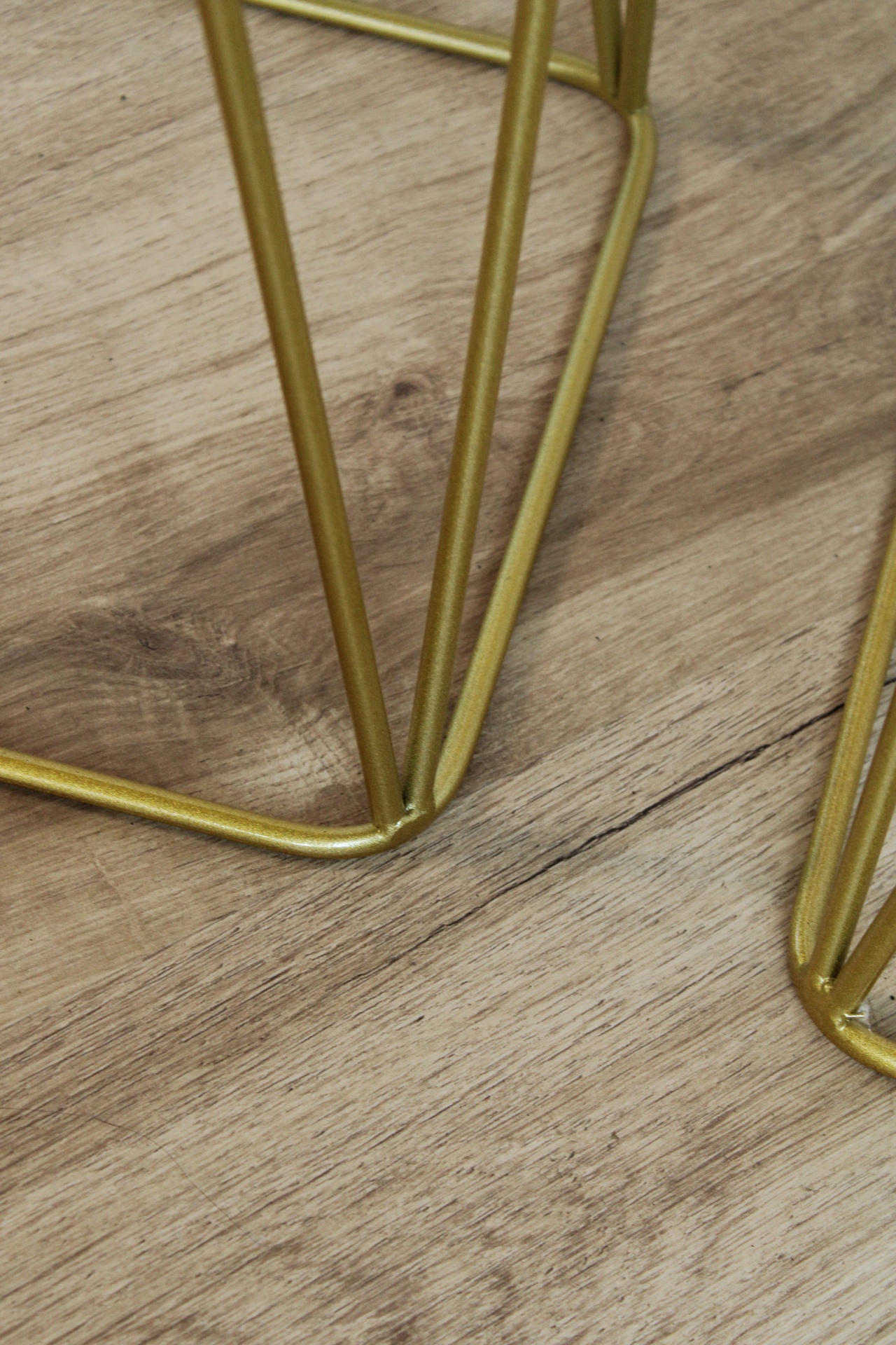 Estrutura metálica dourada sobre chão de madeira clara