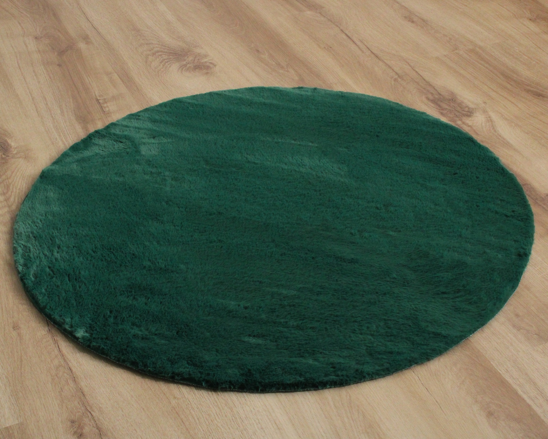 Tapete redondo verde escuro em chão de madeira clara