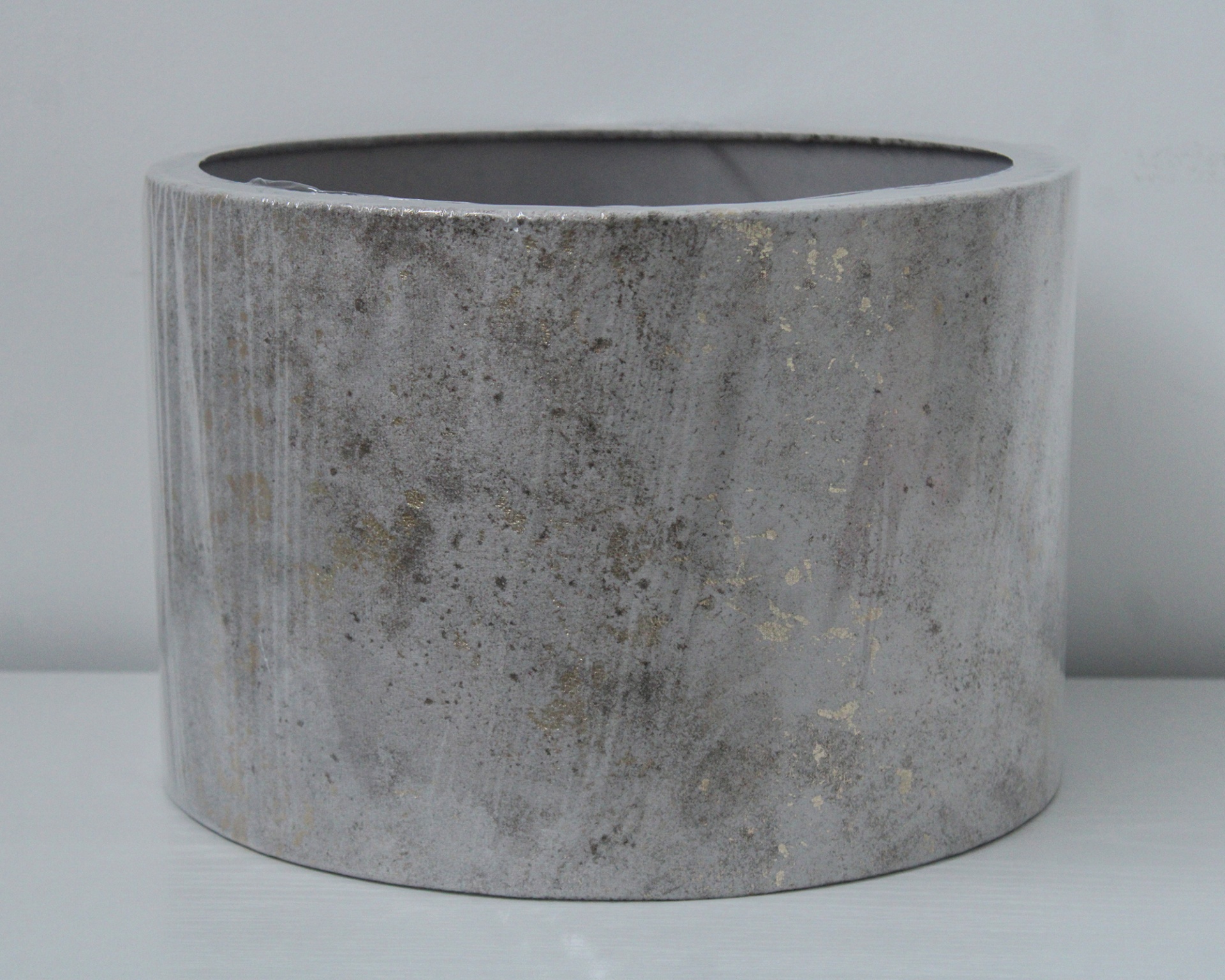 Vaso cilíndrico cinza marmoreado com detalhes dourados em superfície branca