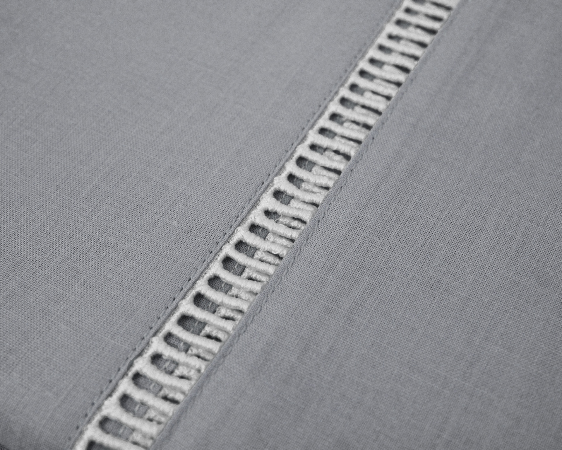 Tecido cinzento com faixa decorativa em malha aberta.