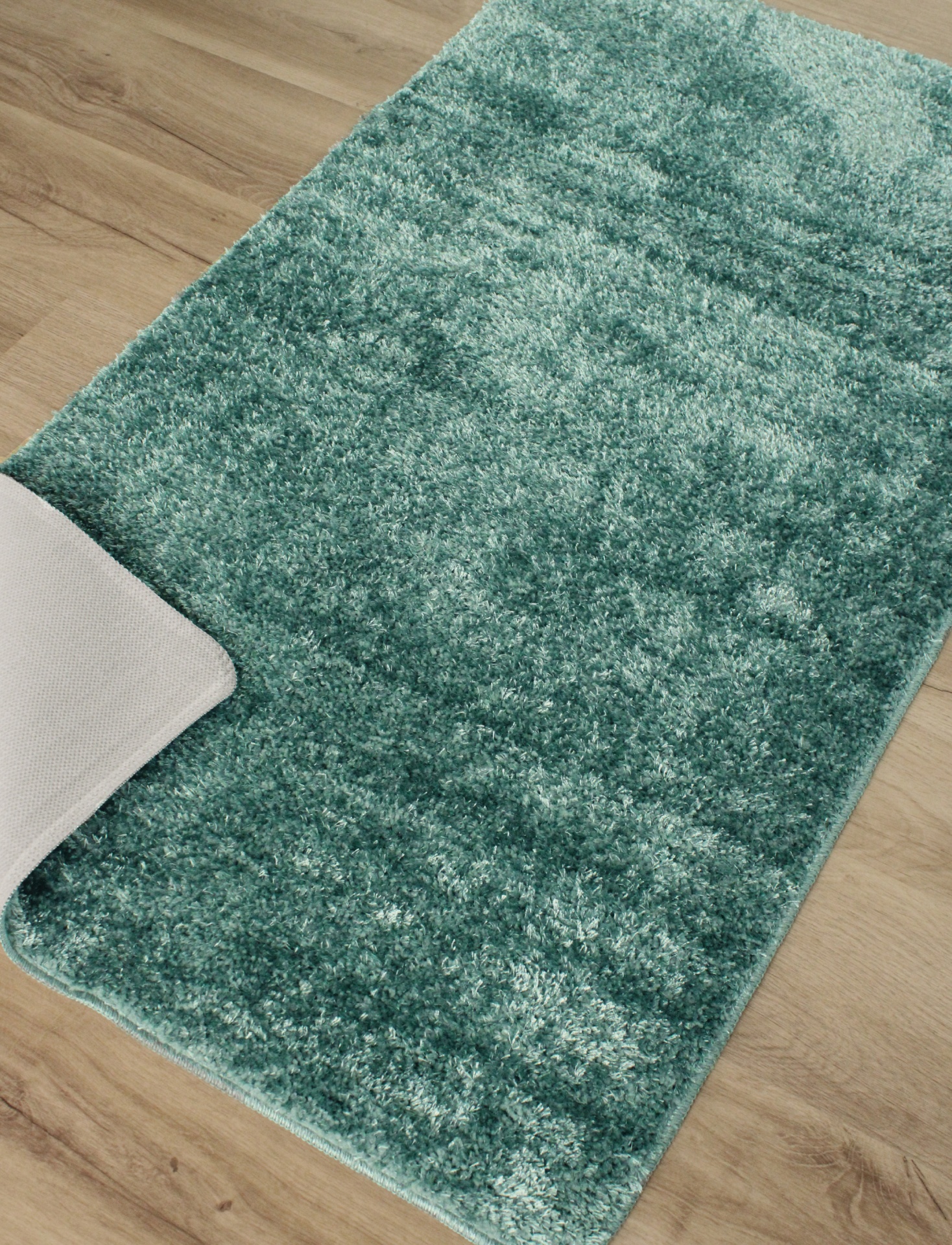 Tapete macio verde com pelo alto sobre chão de madeira clara