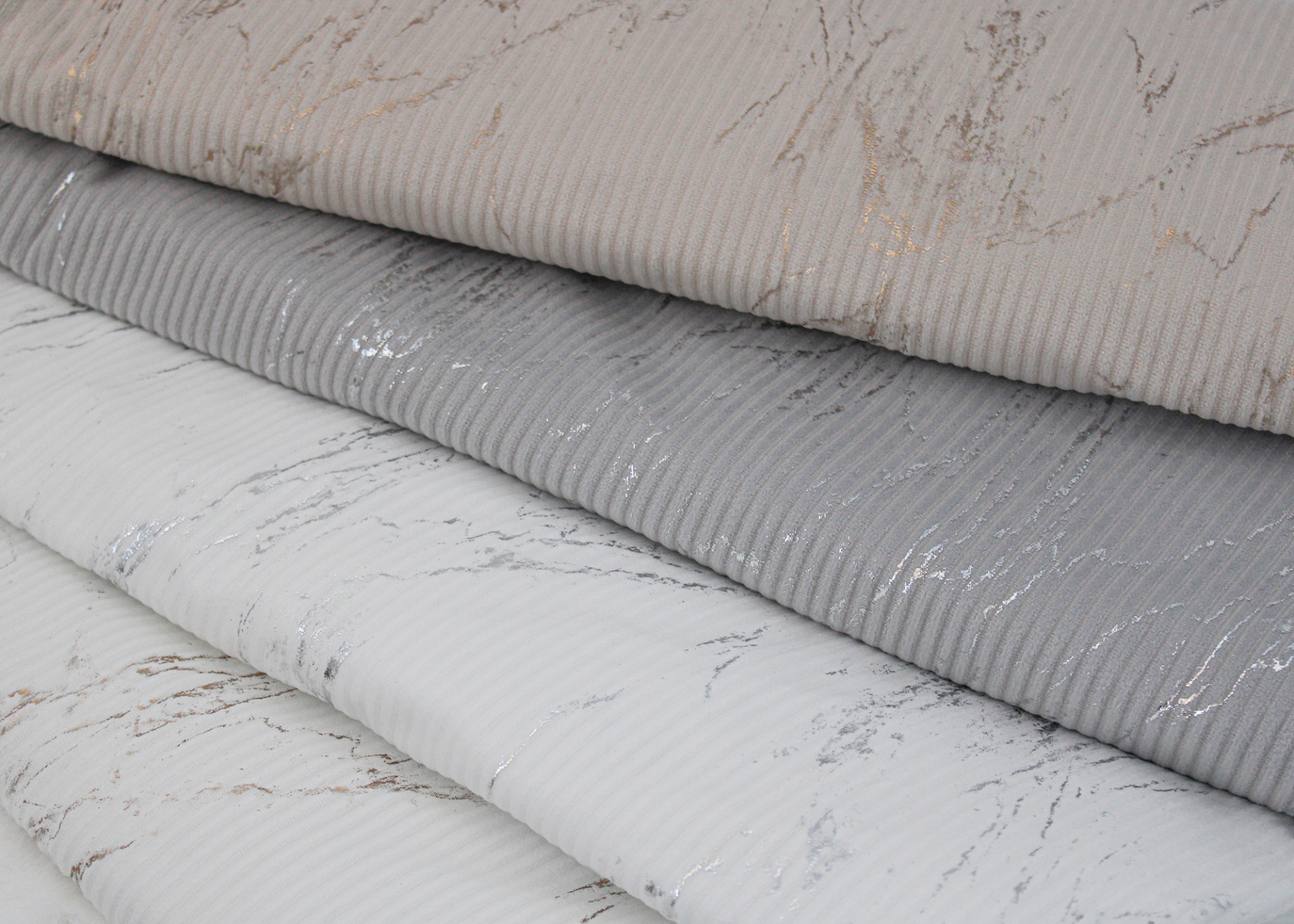 Rolos de tecido com padrões marmoreados e texturas variadas empilhados