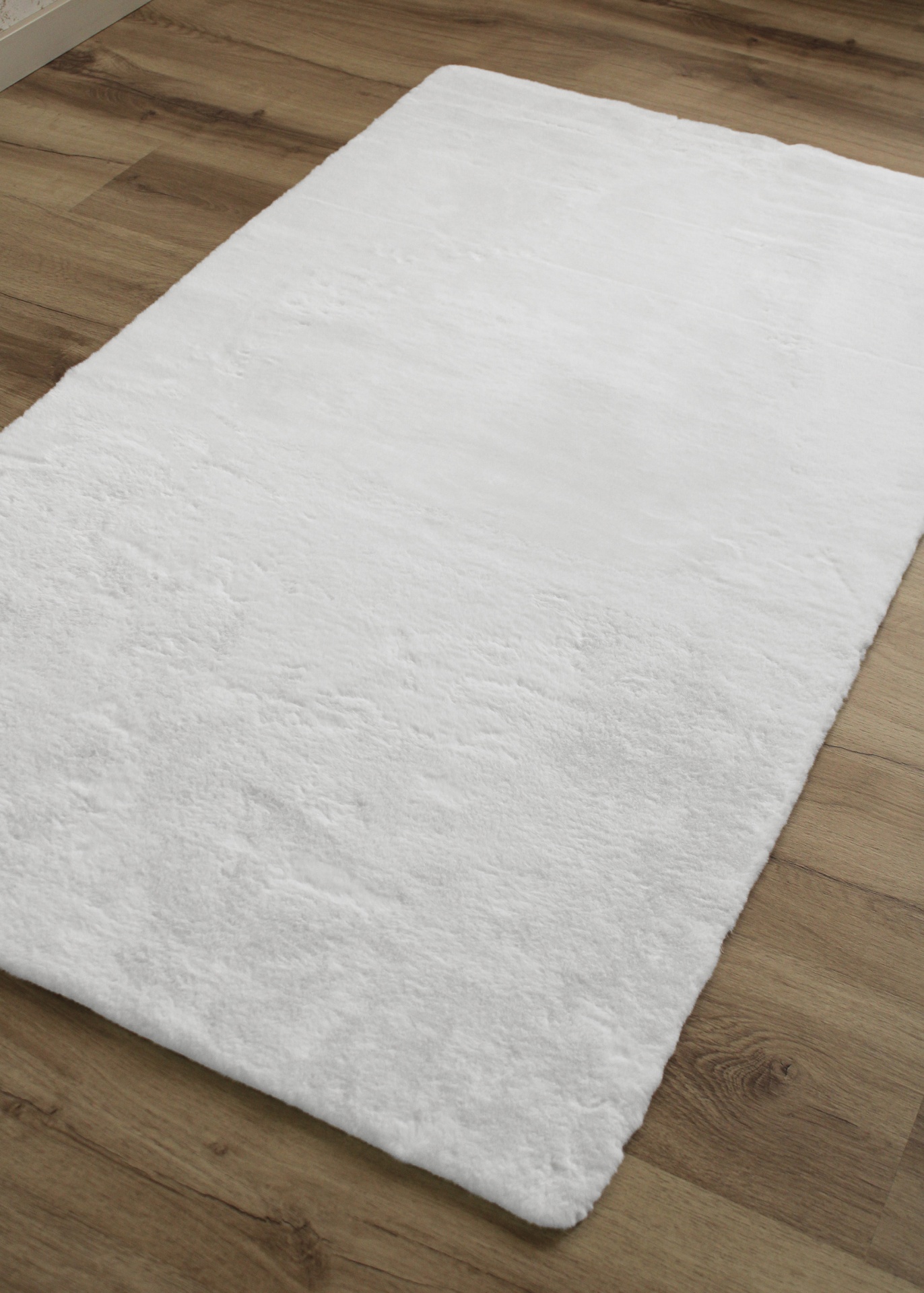 Tapete branco felpudo sobre chão de madeira