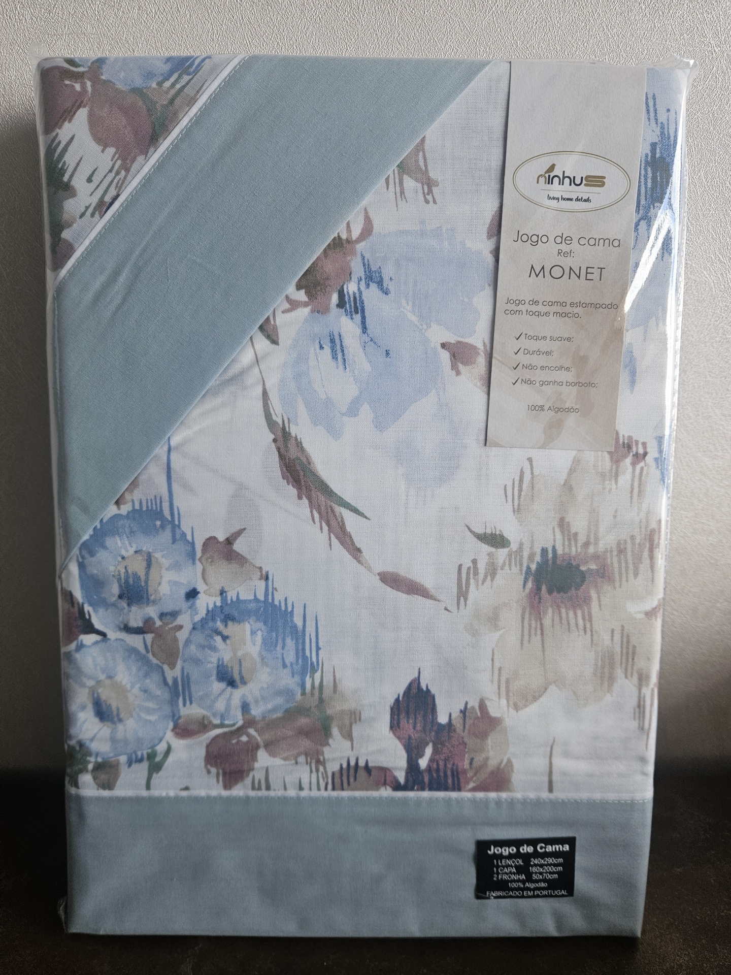 Jogo de cama com estampa floral azul e tecido azul liso em embalagem com etiqueta