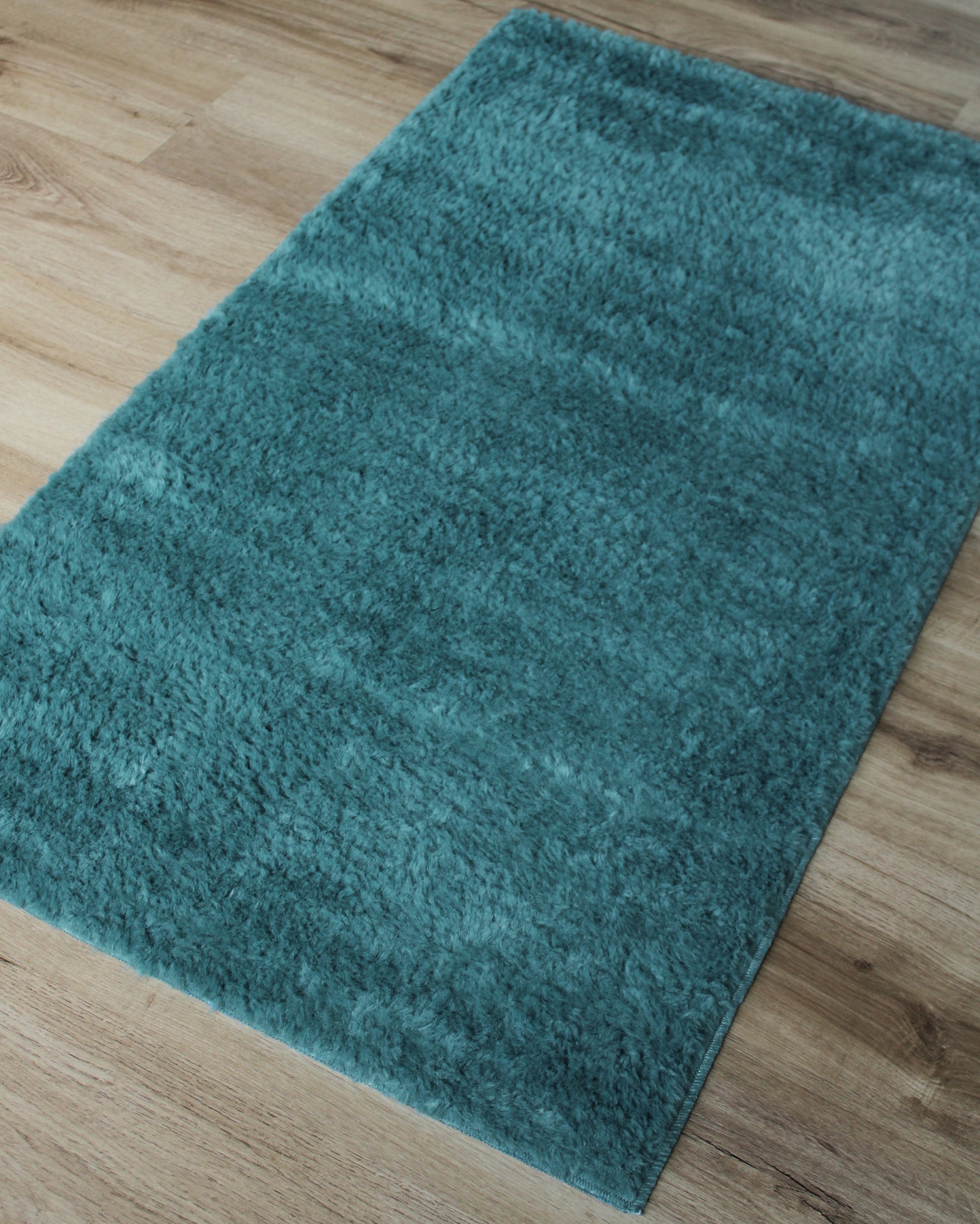 tapete azul turquesa sobre chão de madeira clara