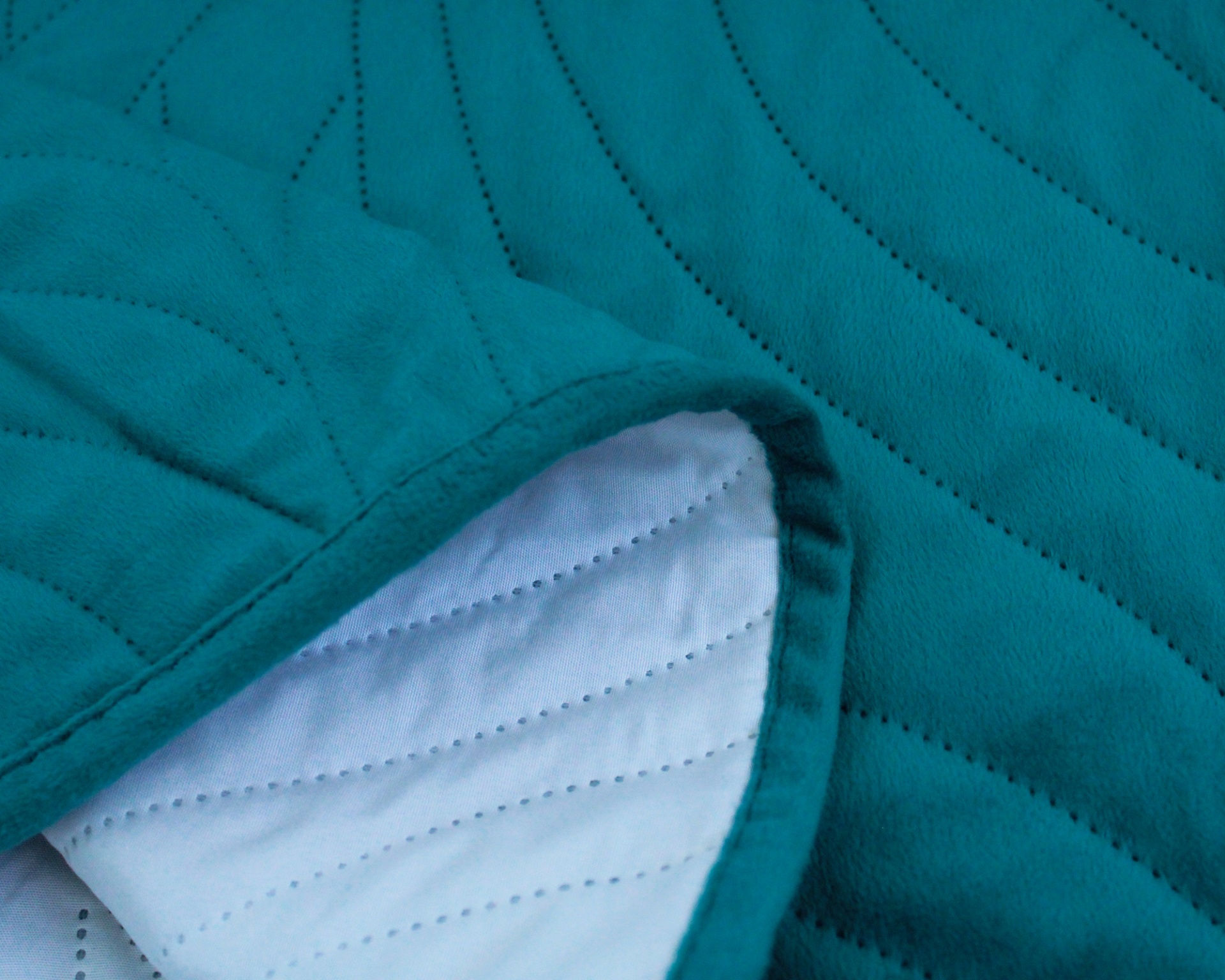 Tecido acolchoado verde-azulado com interior branco e costuras onduladas.