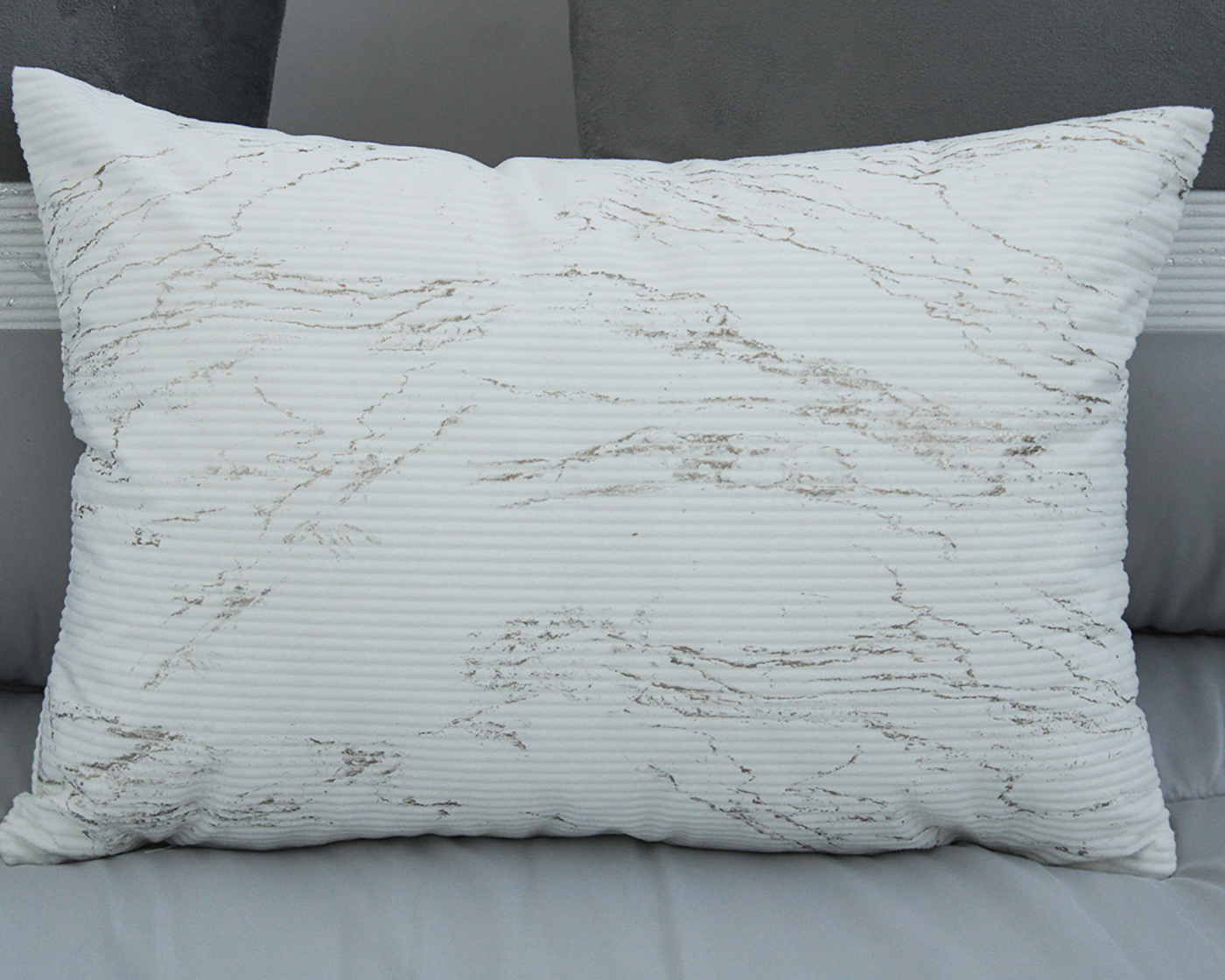 Almofada branca com padrão cinzento sobre sofá cinzento claro