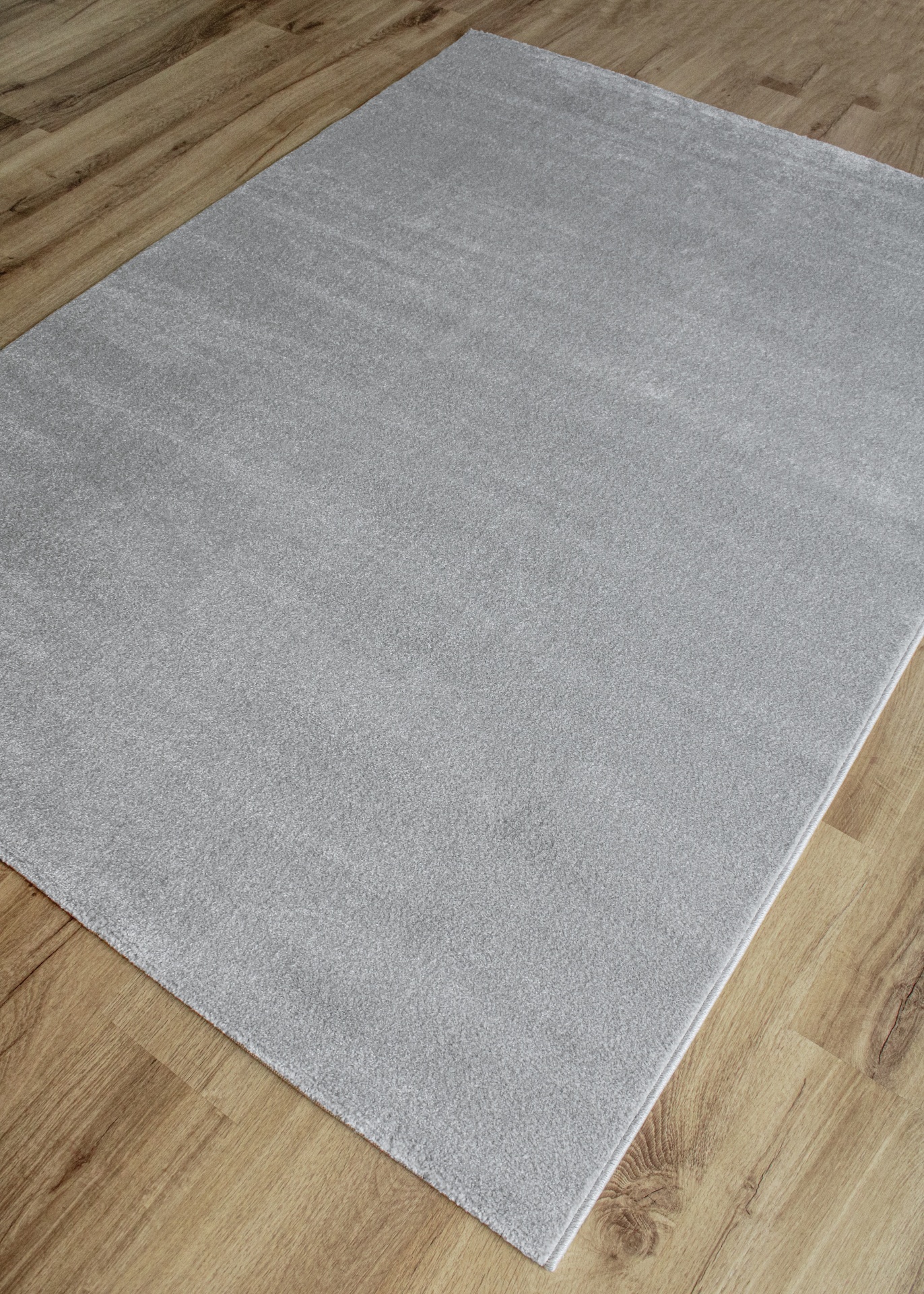 Tapete cinza claro sobre chão de madeira clara