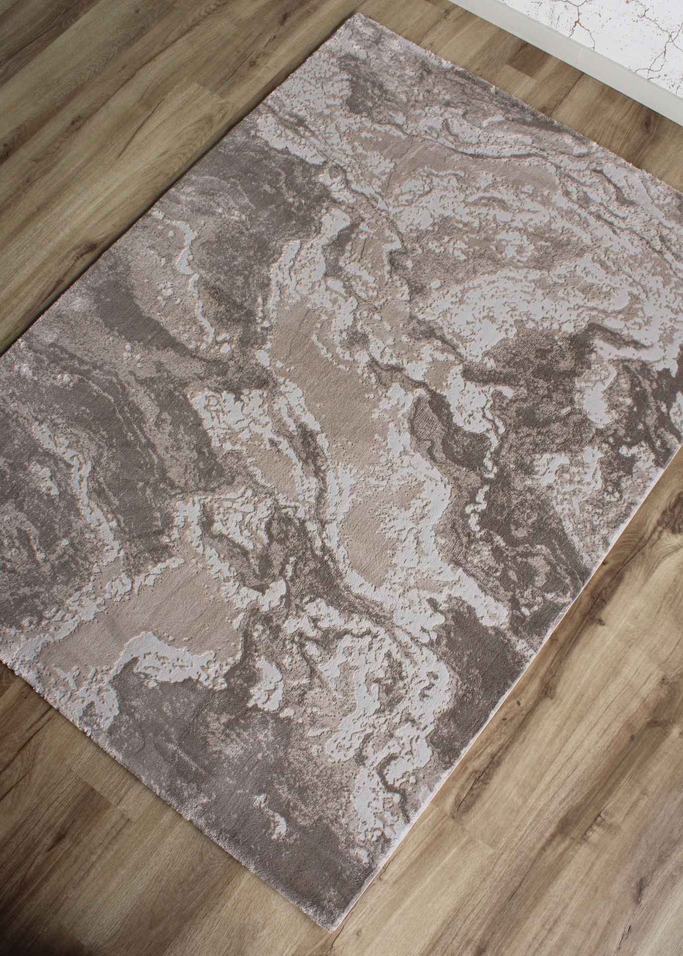 Tapete abstrato cinzento e bege sobre chão de madeira clara