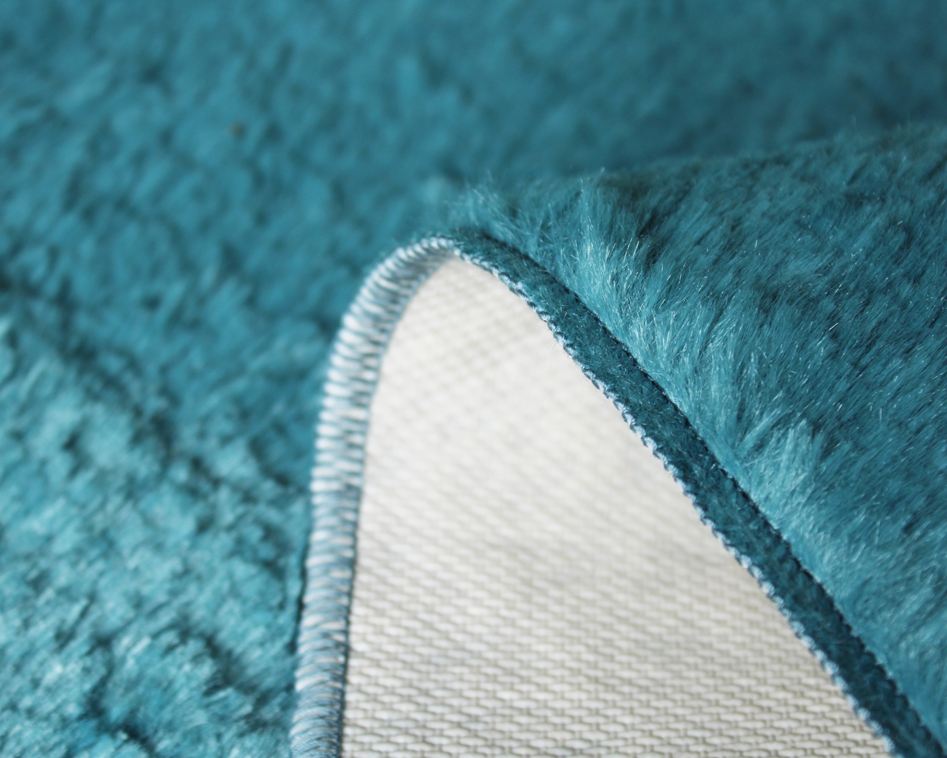 Tapete azul turquesa felpudo com borda costurada e verso branco quadriculado