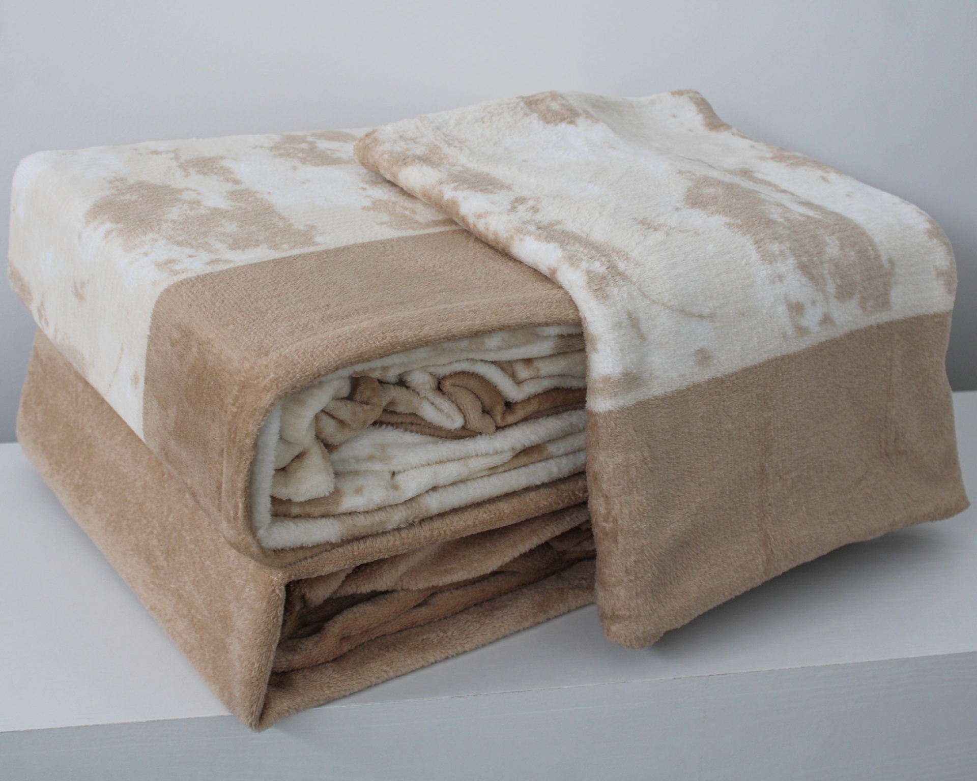 Manta de tecido macio bege e creme com padrão manchado dobrada