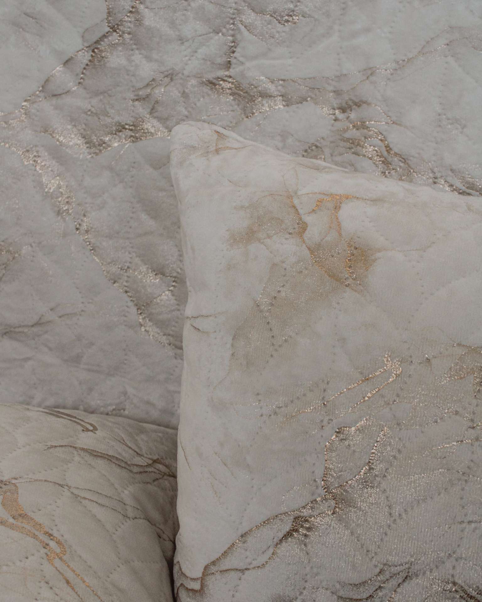 Almofadas e capa de edredão em tecido com padrão marmoreado bege e dourado