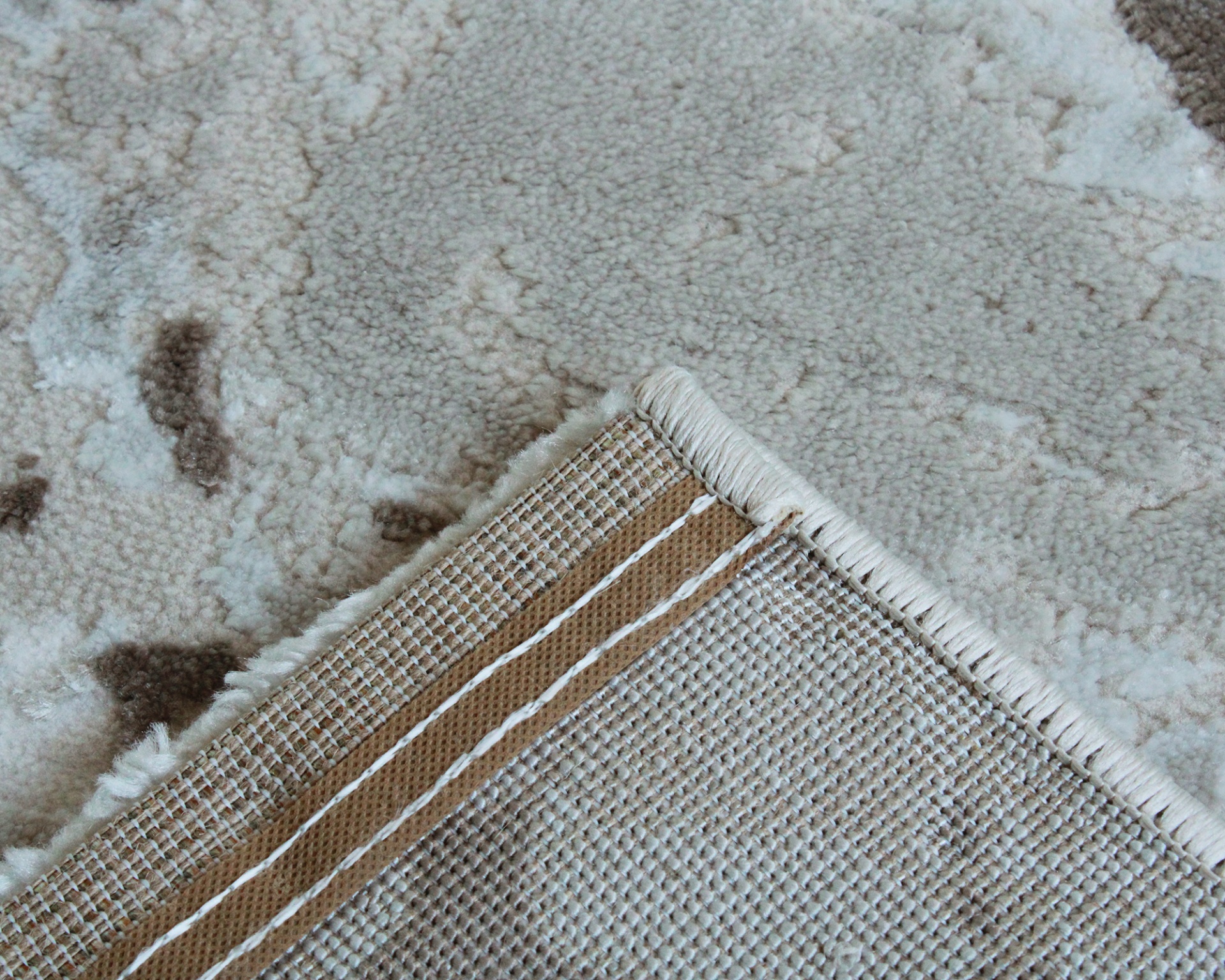 Tapete bege e castanho com textura felpuda e bordas trançadas