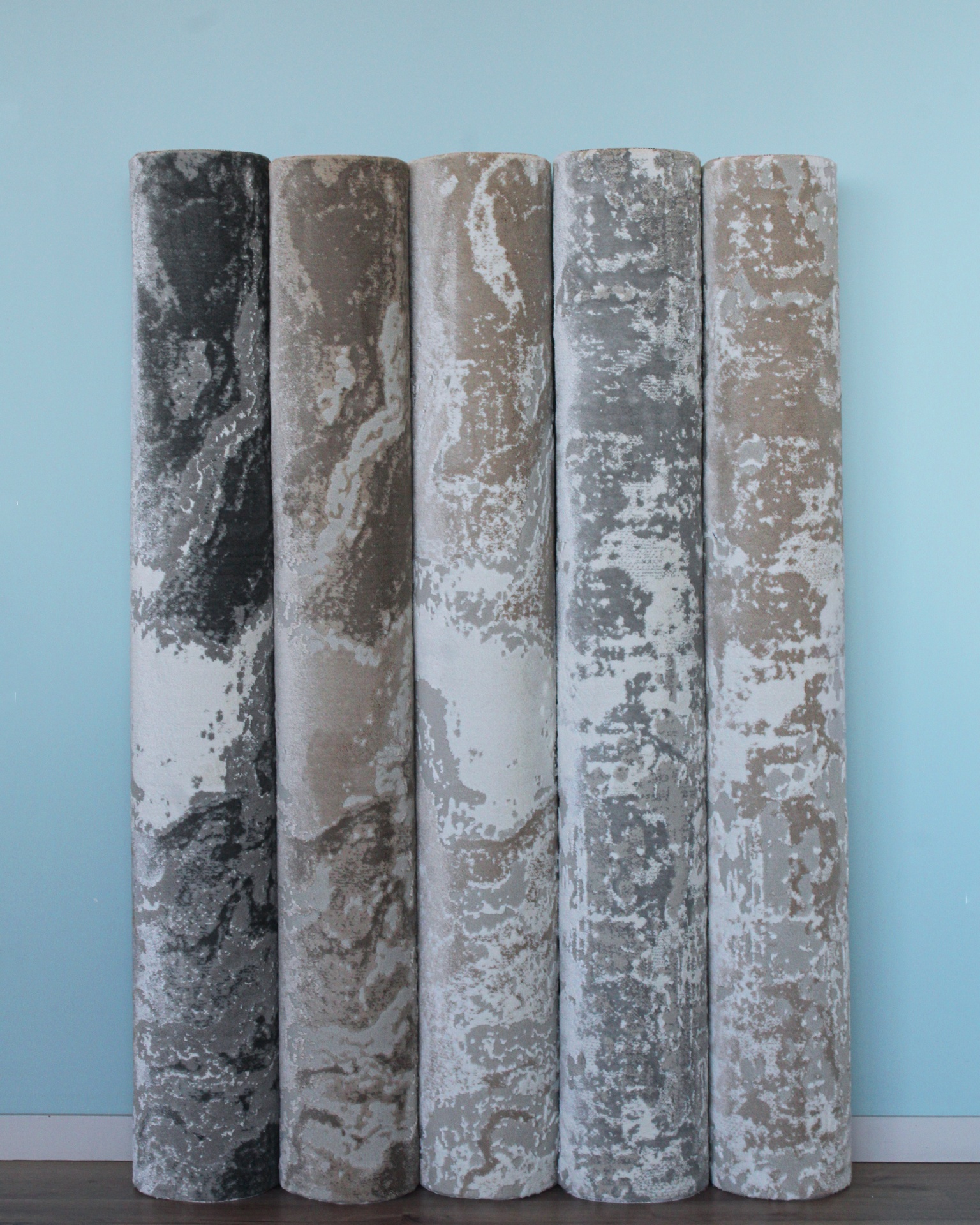 Cinco rolos de tecido com padrão abstrato em cinza, branco e bege