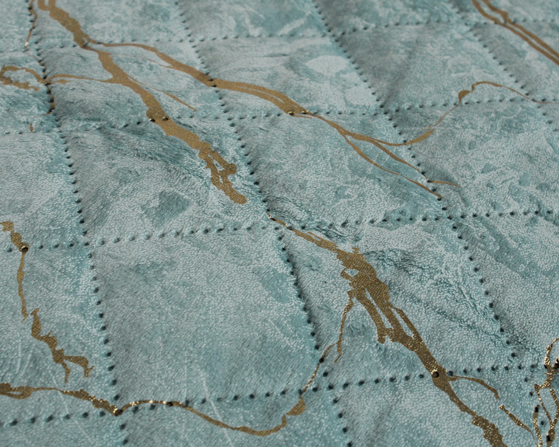 Tecido azul claro acolchoado com padrões dourados e costuras visíveis