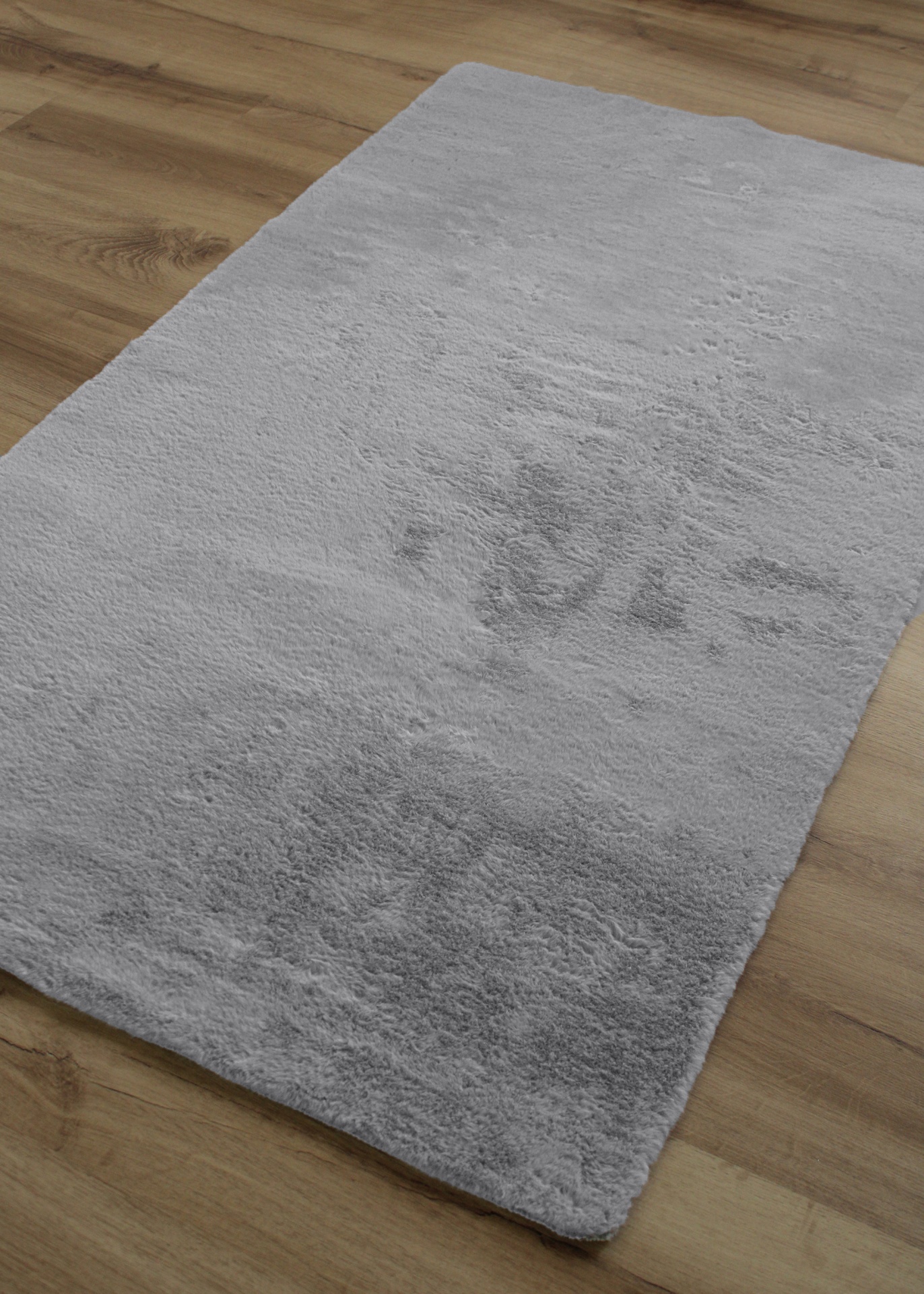 Tapete cinzento claro felpudo sobre chão de madeira