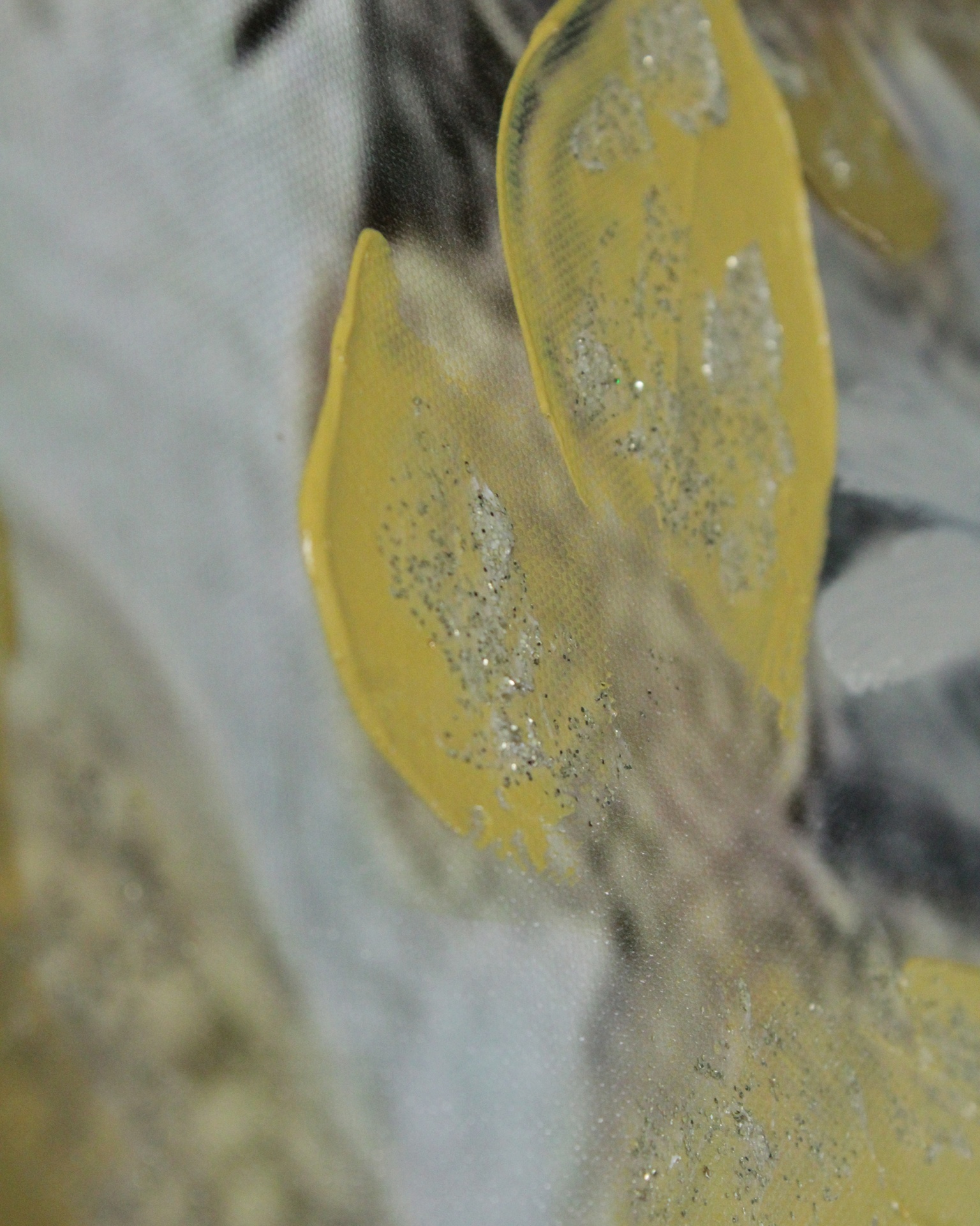 Folhas amarelas com glitter prateado sobre superfície cinza