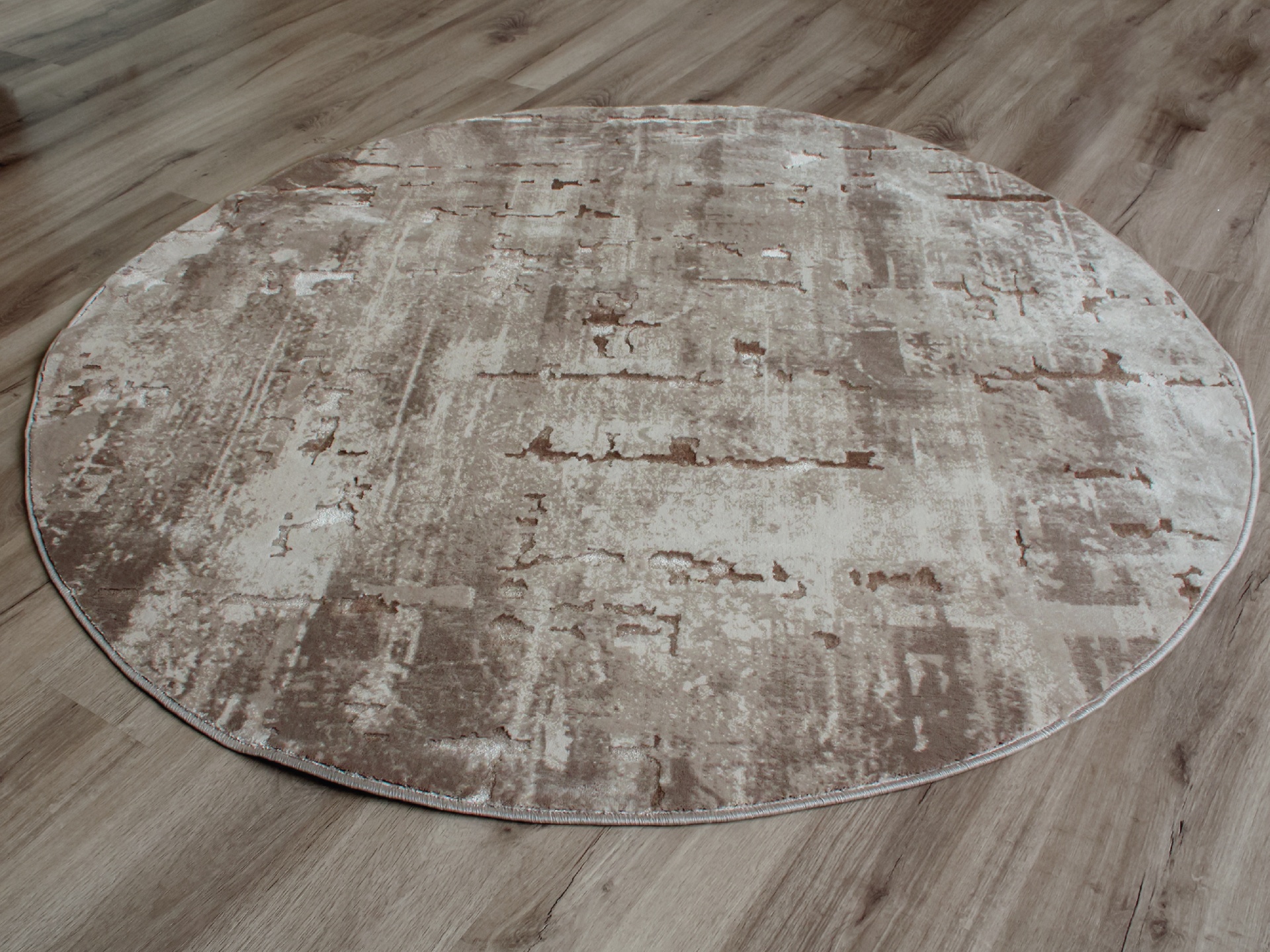 Tapete redondo bege e castanho em chão de madeira clara
