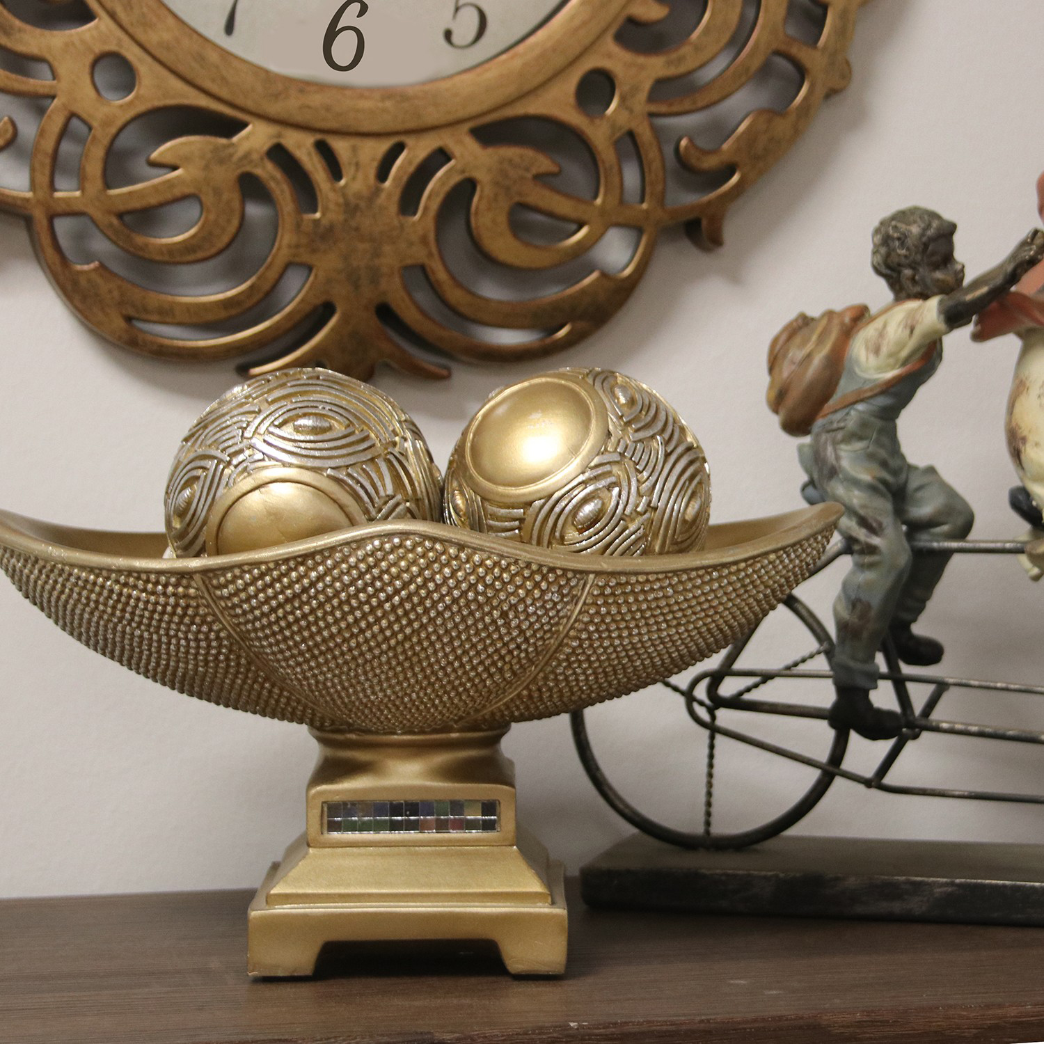 Decoração dourada com bolas texturizadas e base, junto a figura de menino com mochila